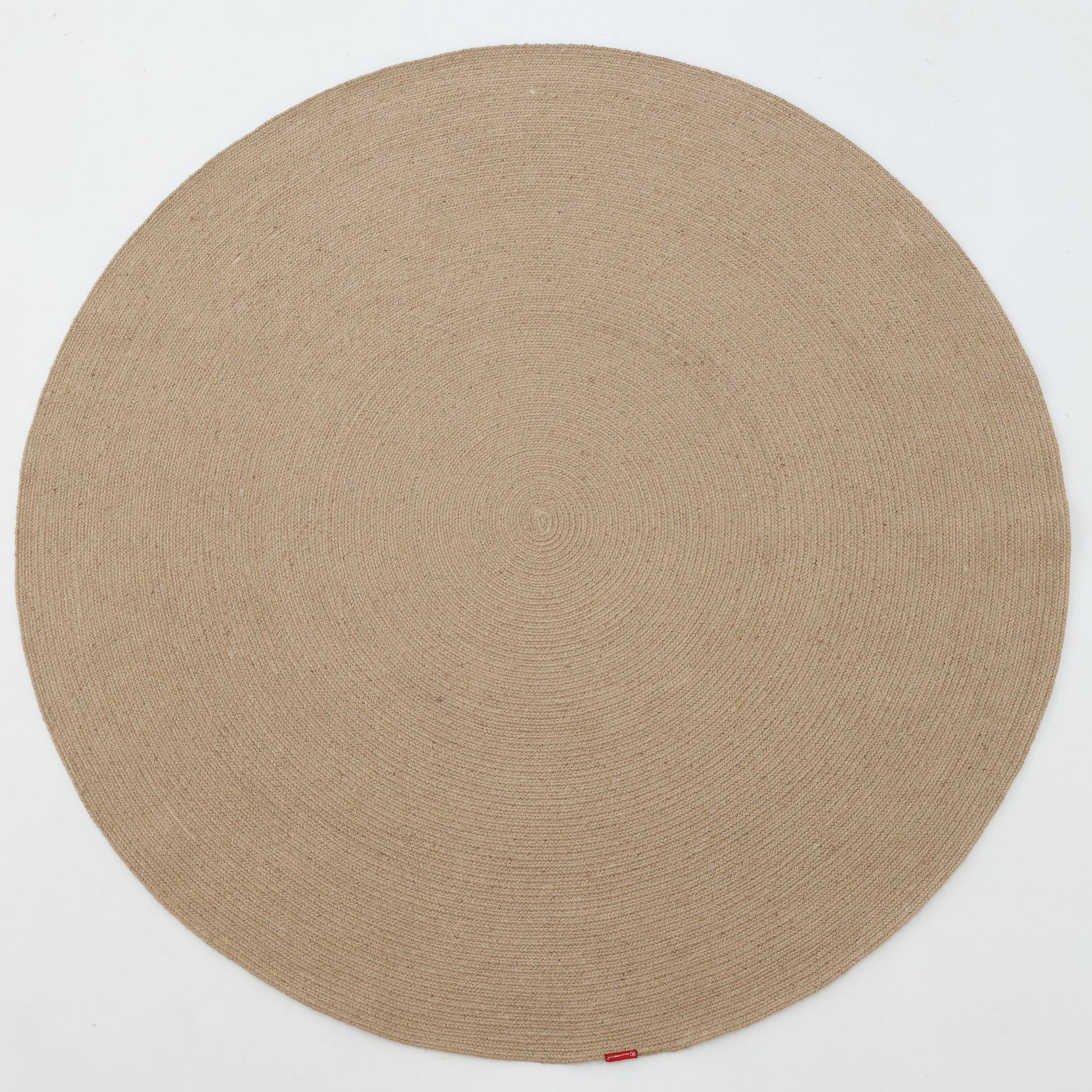 The RAMSHA HOME Stunning Handmade Jute Indoor & Outdoor Round Braided Rug - BR 014 in beige features a subtle circular pattern and a small red tag on its edge, displayed on a white background.