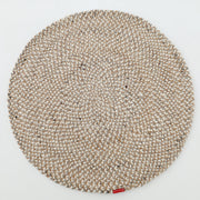 The RAMSHA HOME Natural Color Dining Room Jute Area Braided Rug - BR 096, a round beige and white rug with a braided texture, is shown on a white background with a small red label attached to its edge.