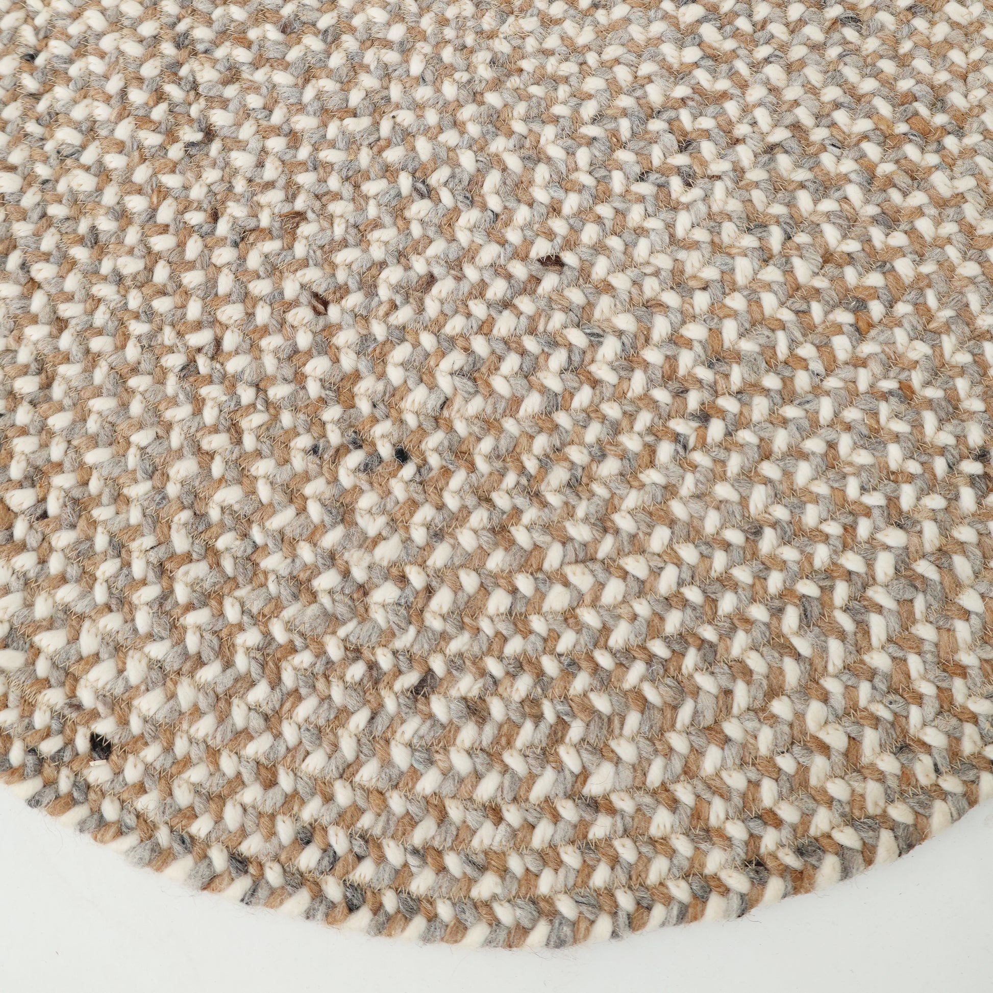 Close-up of the RAMSHA HOME Natural Color Dining Room Jute Area Braided Rug - BR 096, showcasing its round shape and modern minimalist design in tan, gray, and white. The texture of this neutral rug stands out clearly against the white background.