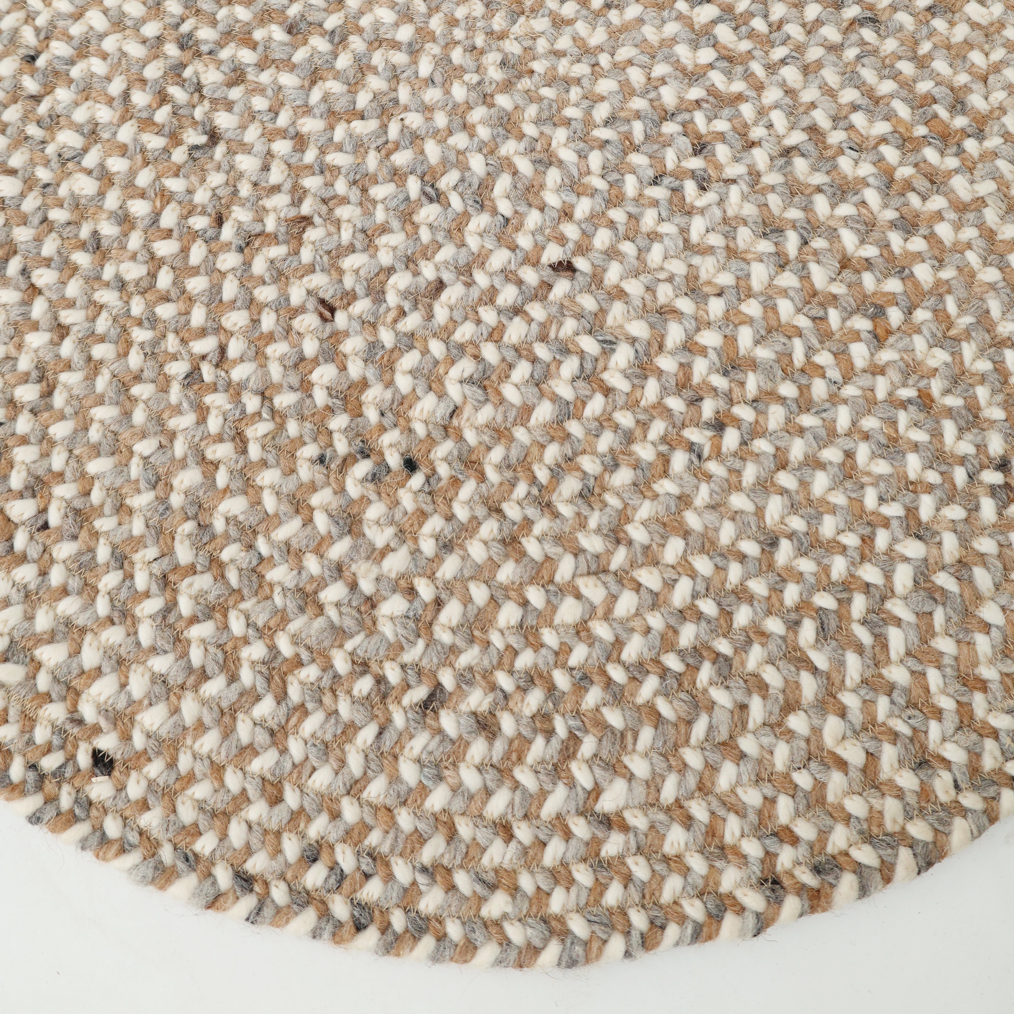 Close-up of the RAMSHA HOME Natural Color Dining Room Jute Area Braided Rug - BR 096, showcasing its round shape and modern minimalist design in tan, gray, and white. The texture of this neutral rug stands out clearly against the white background.