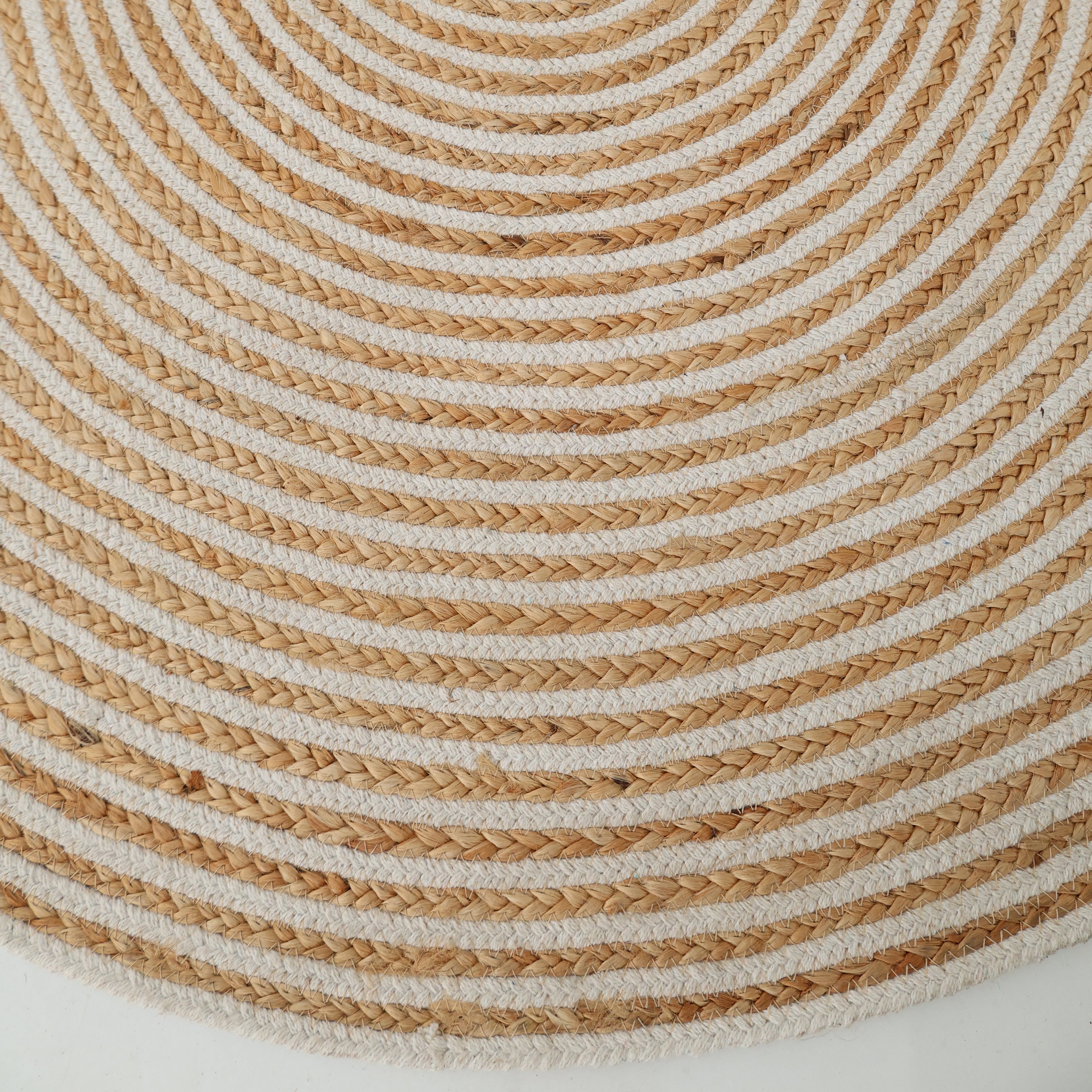 Close-up of the Handmade Natural & White Color Braided Jute Round Rug (BR 012), with alternating natural and white concentric circles forming a textured spiral pattern on a white background.