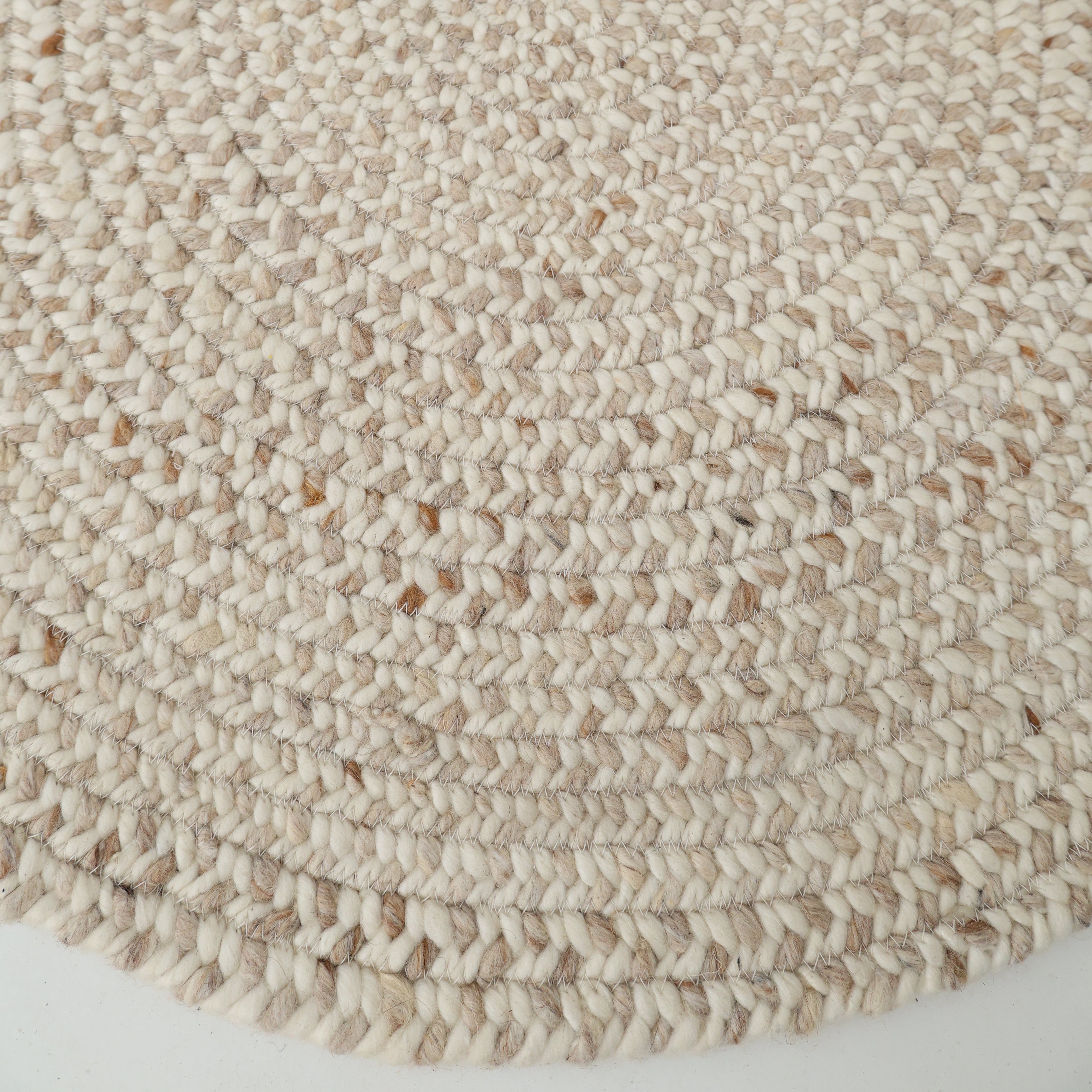 Close-up of the RAMSHA HOME Natural Color Home Decor Round Jute Rug - BR 095, featuring a textured braided pattern in beige and light brown, displayed on a white surface.