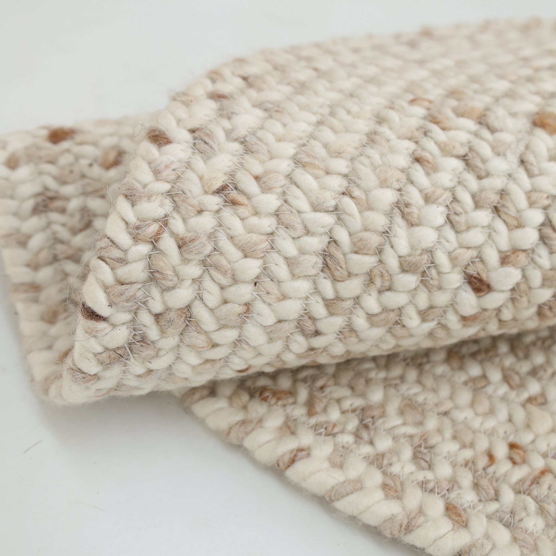 Close-up of the Natural Color Home Decor Round Jute Rug - BR 095 by RAMSHA HOME on a white surface, highlighting its thick woven texture and detailed pattern.