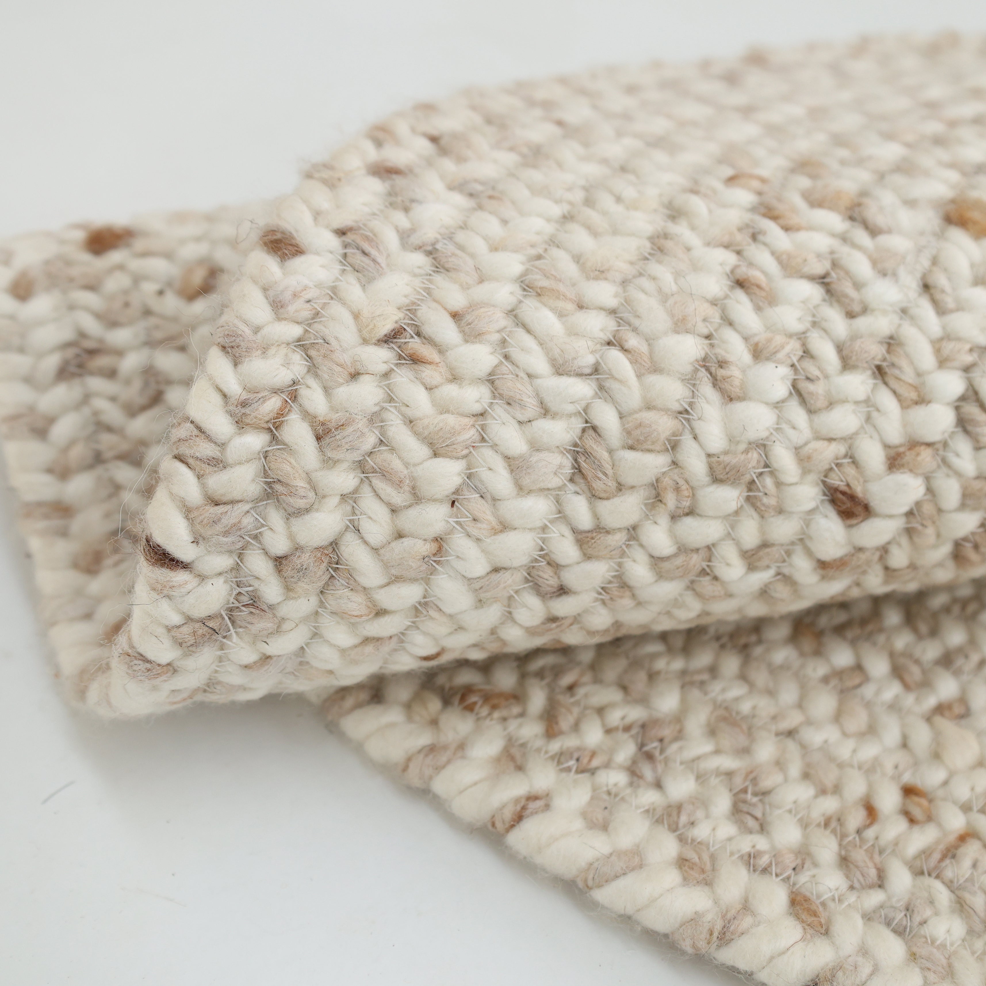 Close-up of the Natural Color Home Decor Round Jute Rug - BR 095 by RAMSHA HOME on a white surface, highlighting its thick woven texture and detailed pattern.