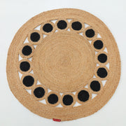The RAMSHA HOME Jute Natural Rug Round Natural & Black BR-050 is a round jute rug made from natural fibers, featuring a ring of black circles near the edge—a bold accent against a white background.
