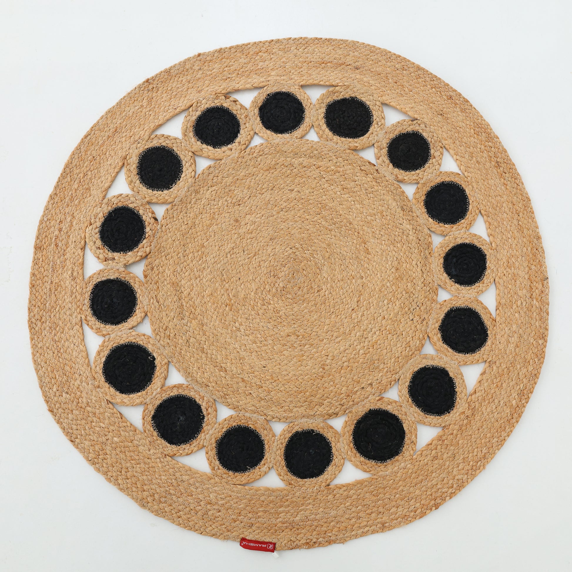The RAMSHA HOME Jute Natural Rug Round Natural & Black BR-050 is a round jute rug made from natural fibers, featuring a ring of black circles near the edge—a bold accent against a white background.