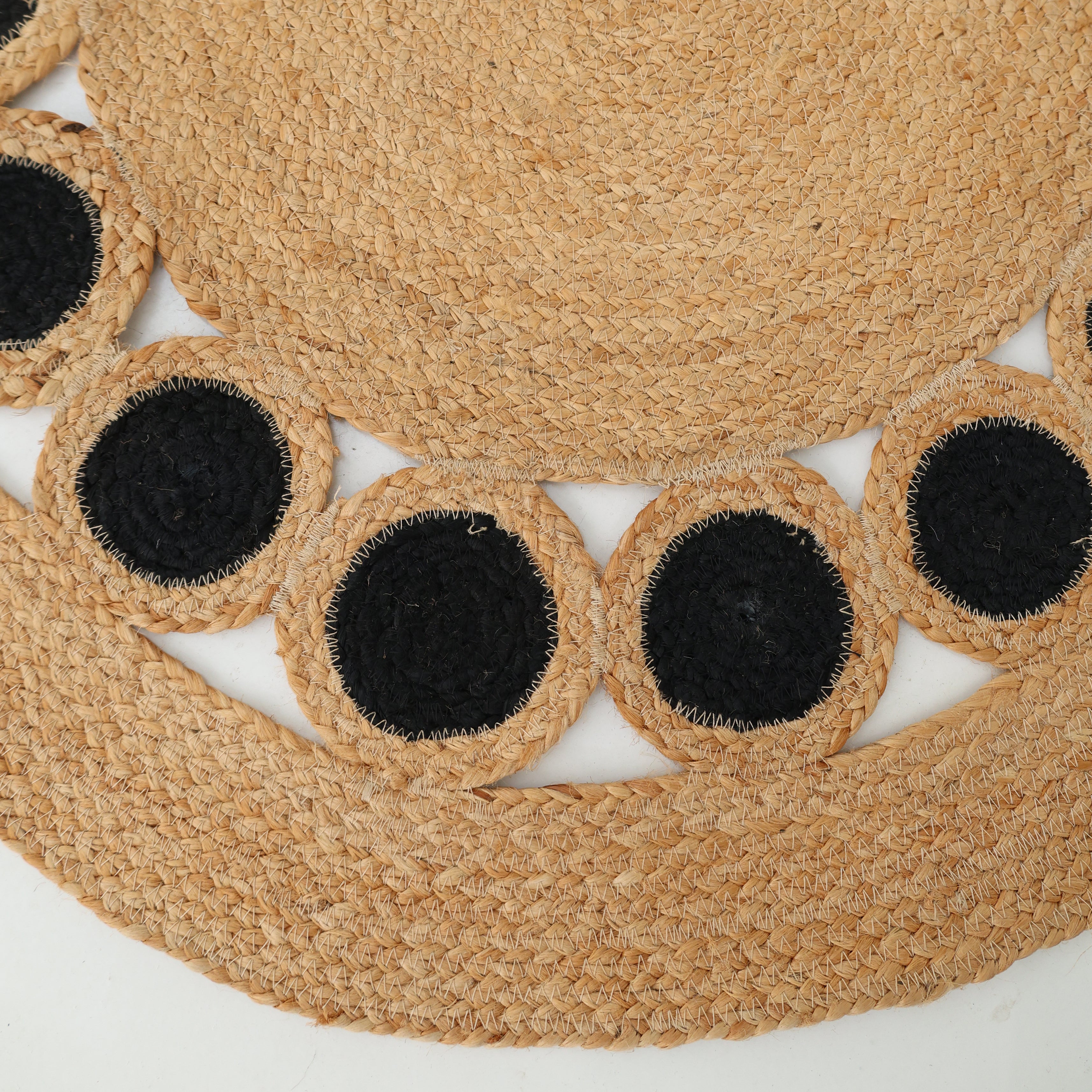 Close-up of the RAMSHA HOME Jute Natural Rug Round Natural & Black BR-050, showing its braided jute design with a circular pattern and black-centered circles stitched along the edge for a decorative border.