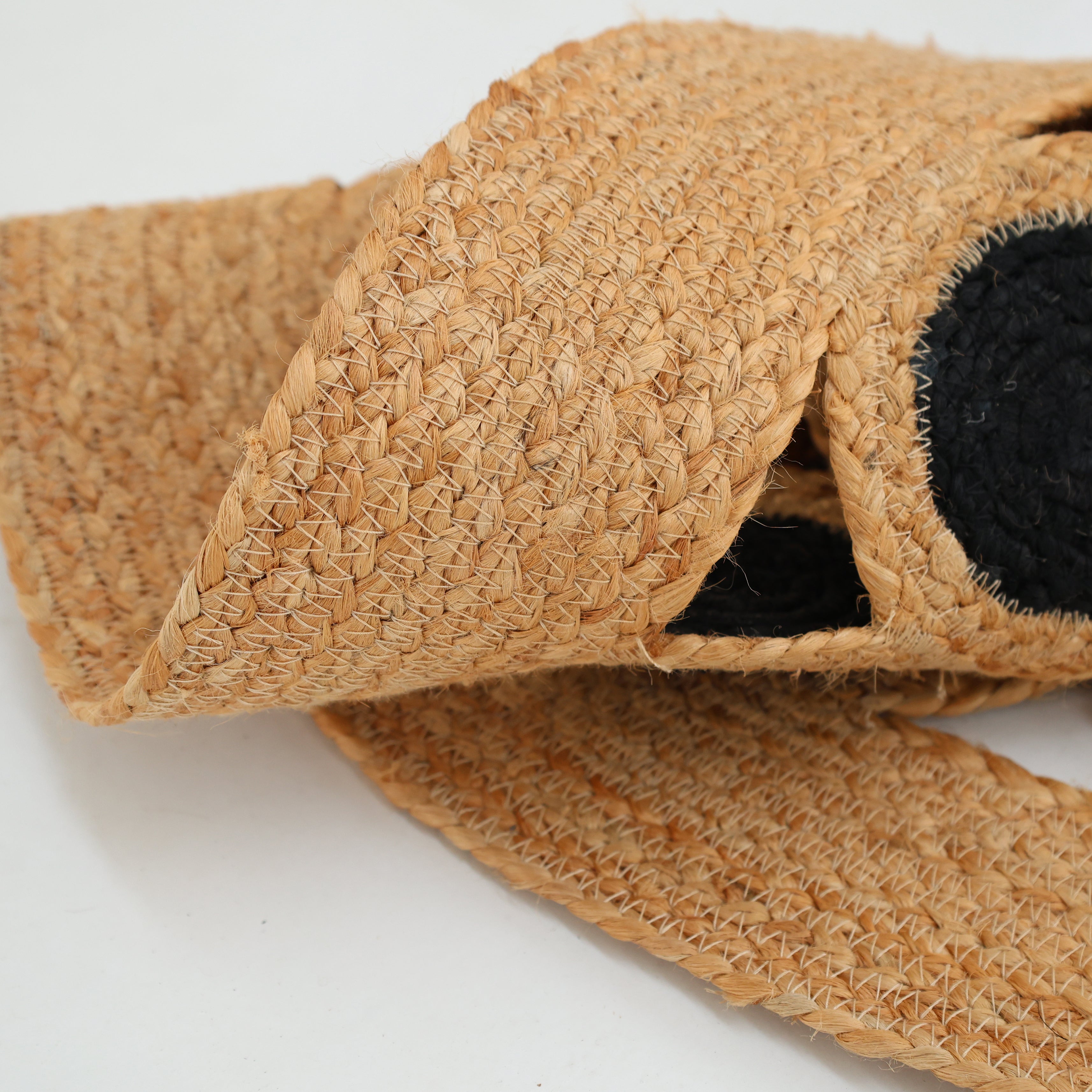 A close-up of the RAMSHA HOME Jute Natural Rug Round Natural & Black BR-050 showcases its rustic texture, with natural jute fibers and a black circular accent resembling woven straw, set against a plain white background.
