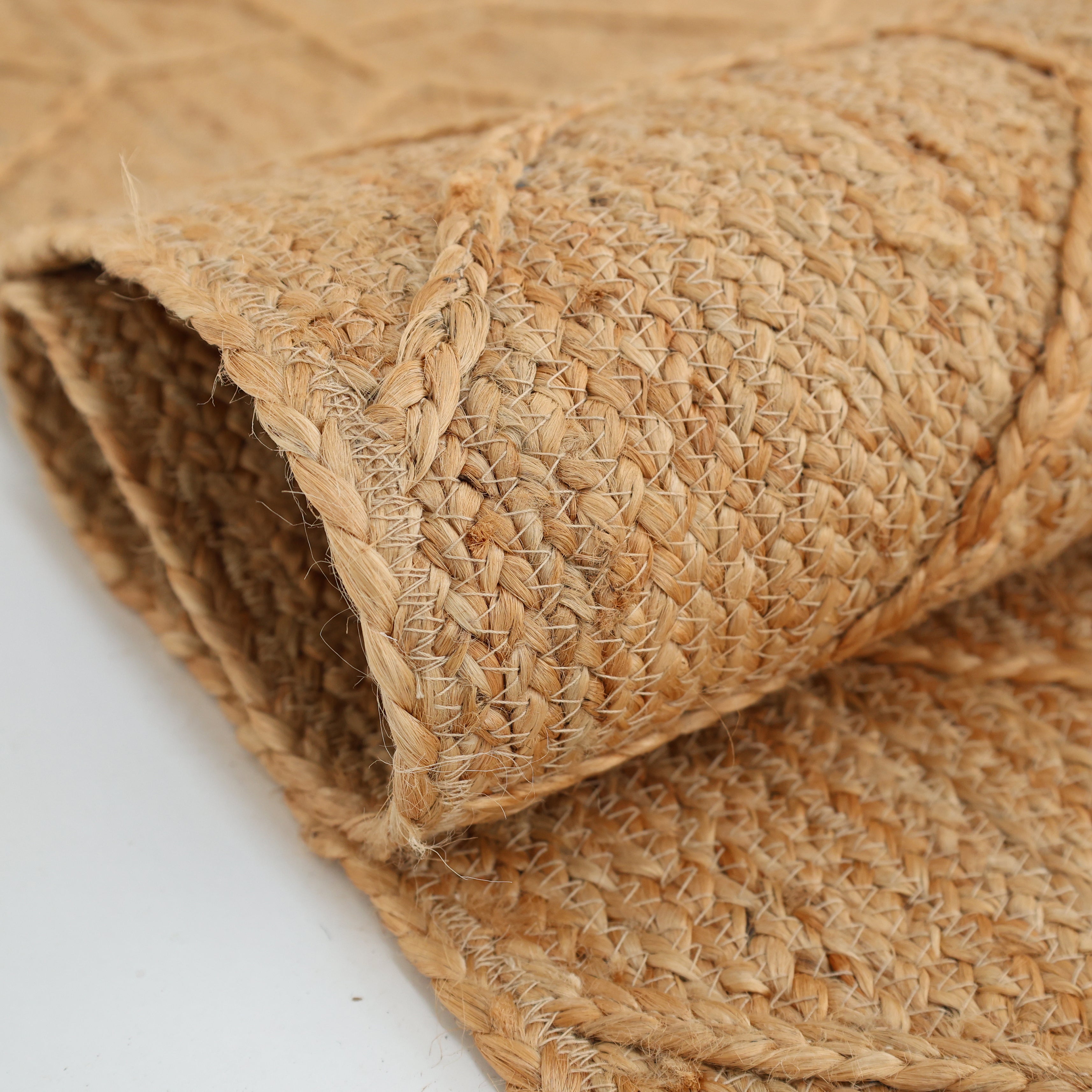 A close-up of the RAMSHA HOME Natural Color Dining Room Jute Area Braided Rug - BR 076 highlights its beige jute texture, durable braided construction, and neat edges against a white background.