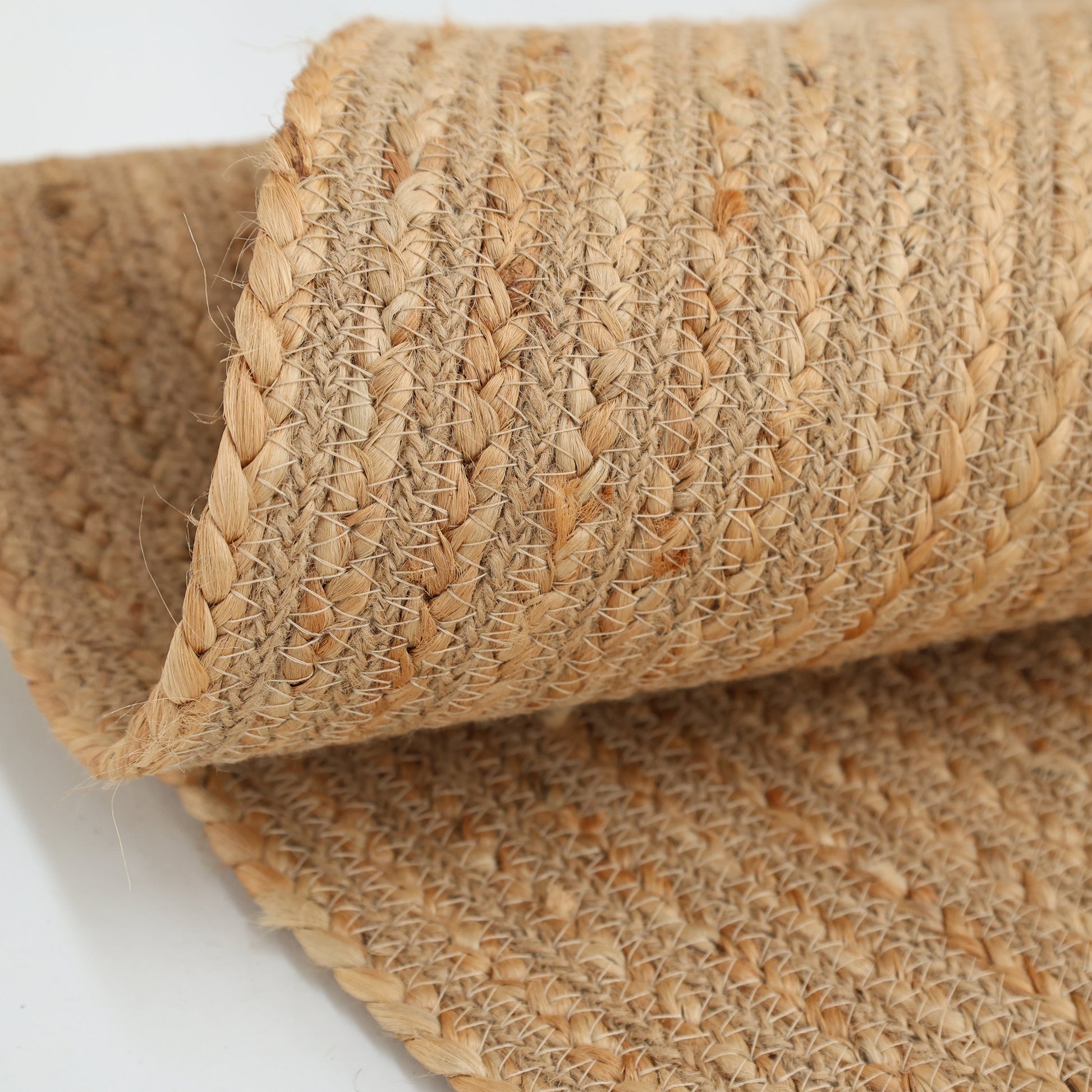 A close-up of the RAMSHA HOME Luxurious Handmade Home Decor Jute Rug Circle - BR 088, showcasing its natural tan braided fibers and textured woven pattern.