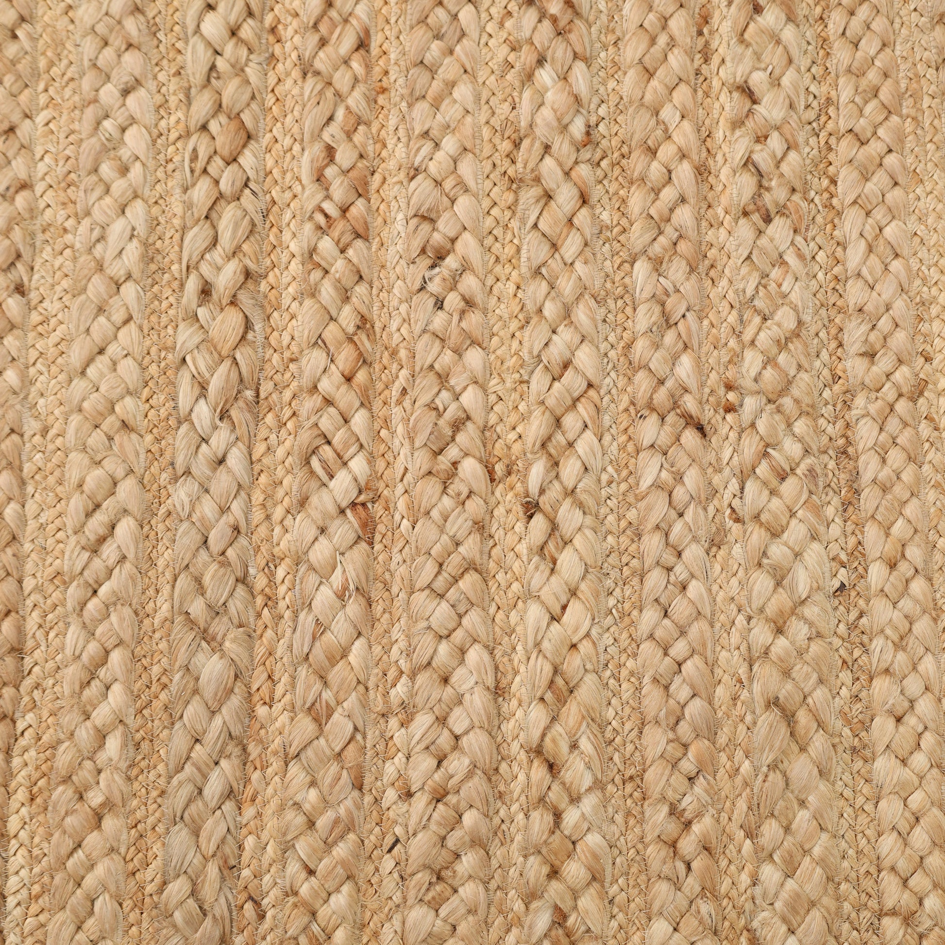 Close-up of the RAMSHA HOME Braided Jute Natural Color Handmade Rug - BR 021, showcasing light brown and beige tones. Woven with interlocking strands, this rug features a textured, repeating striped design.