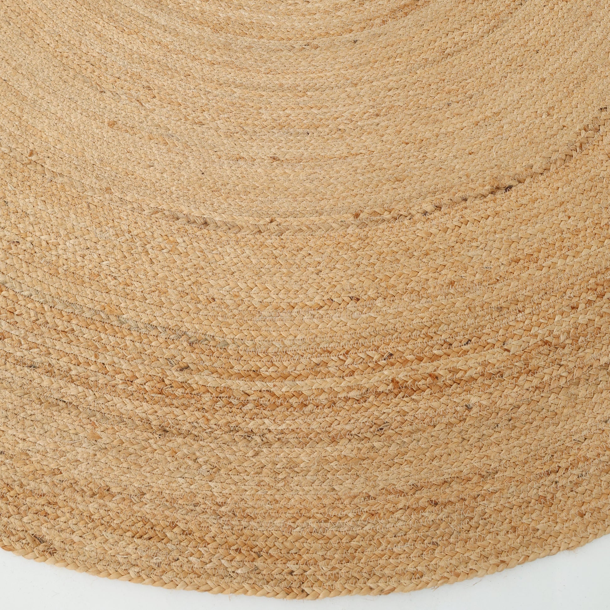 Close-up of the RAMSHA HOME Handmade Jute Braided Rug BR-016, an oval natural area rug with a subtle spiral pattern in tan and beige tones, showing its textured surface as it lies on a white background.