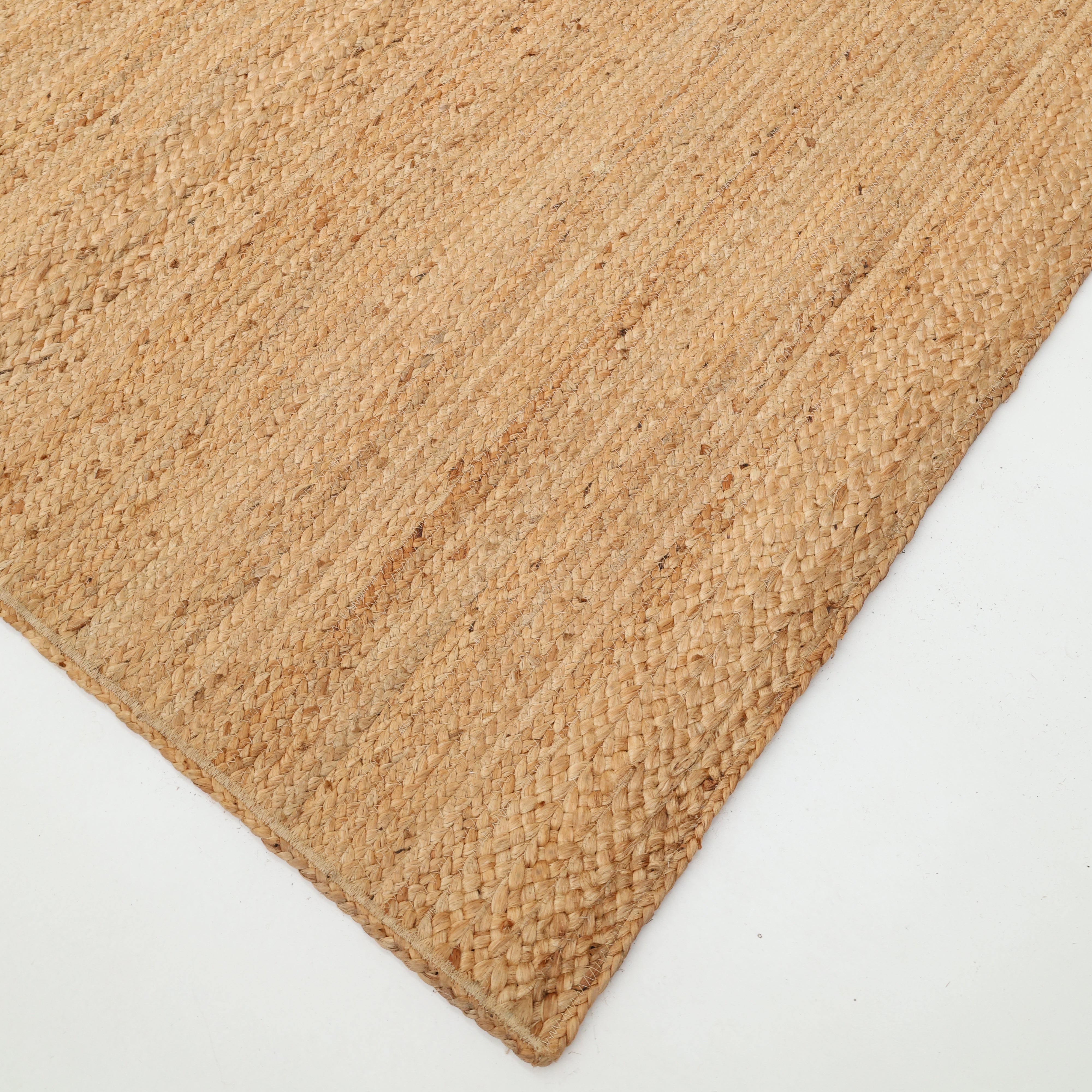 A close-up of the RAMSHA HOME Beautiful Handmade Braided Rug - BR 071 on a white background highlights its natural fiber texture and earthy light brown color.