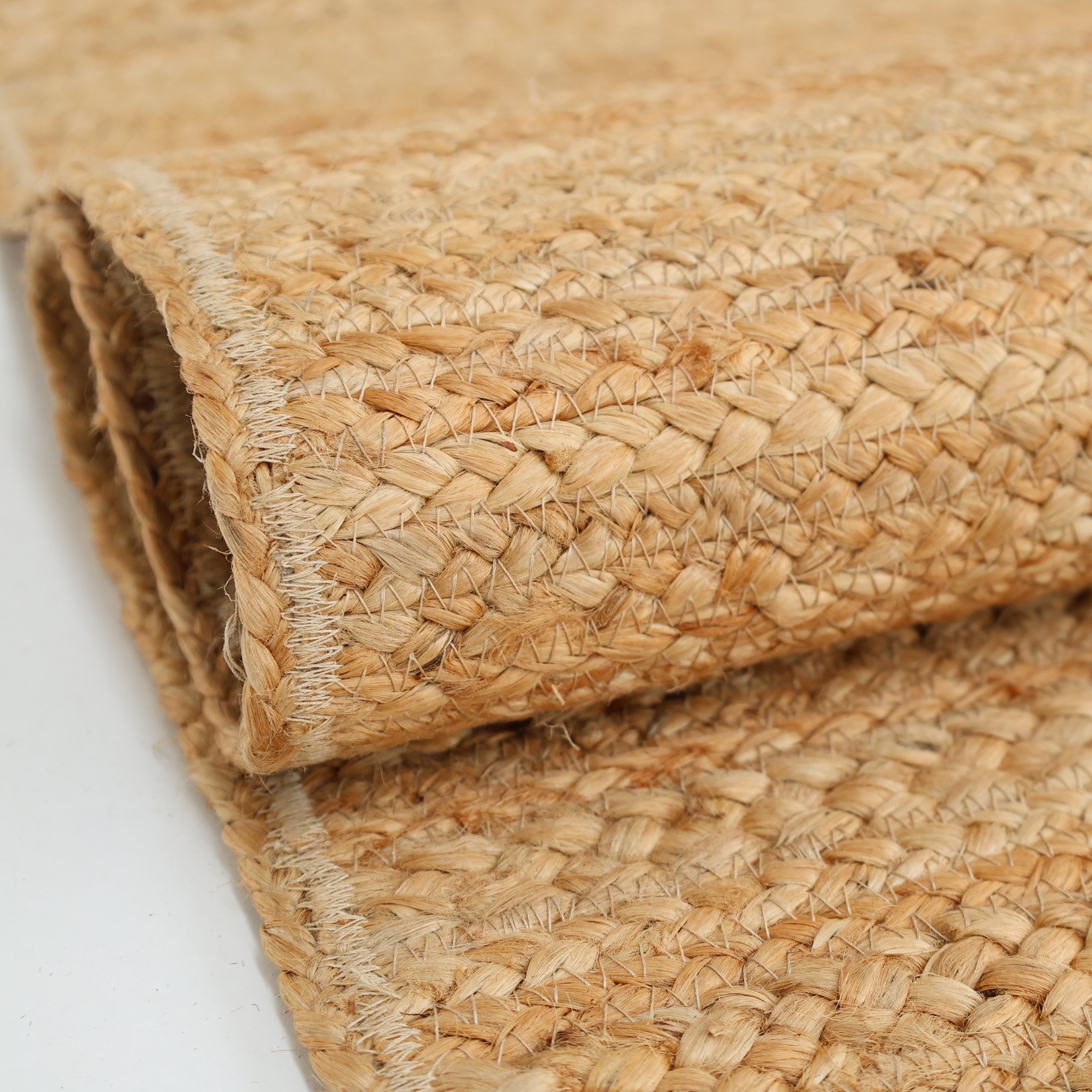 A close-up of the RAMSHA HOME Beautiful Handmade Braided Rug - BR 071, showcasing its thick braided jute fibers and textured surface in light brown tones, displayed on a white background.