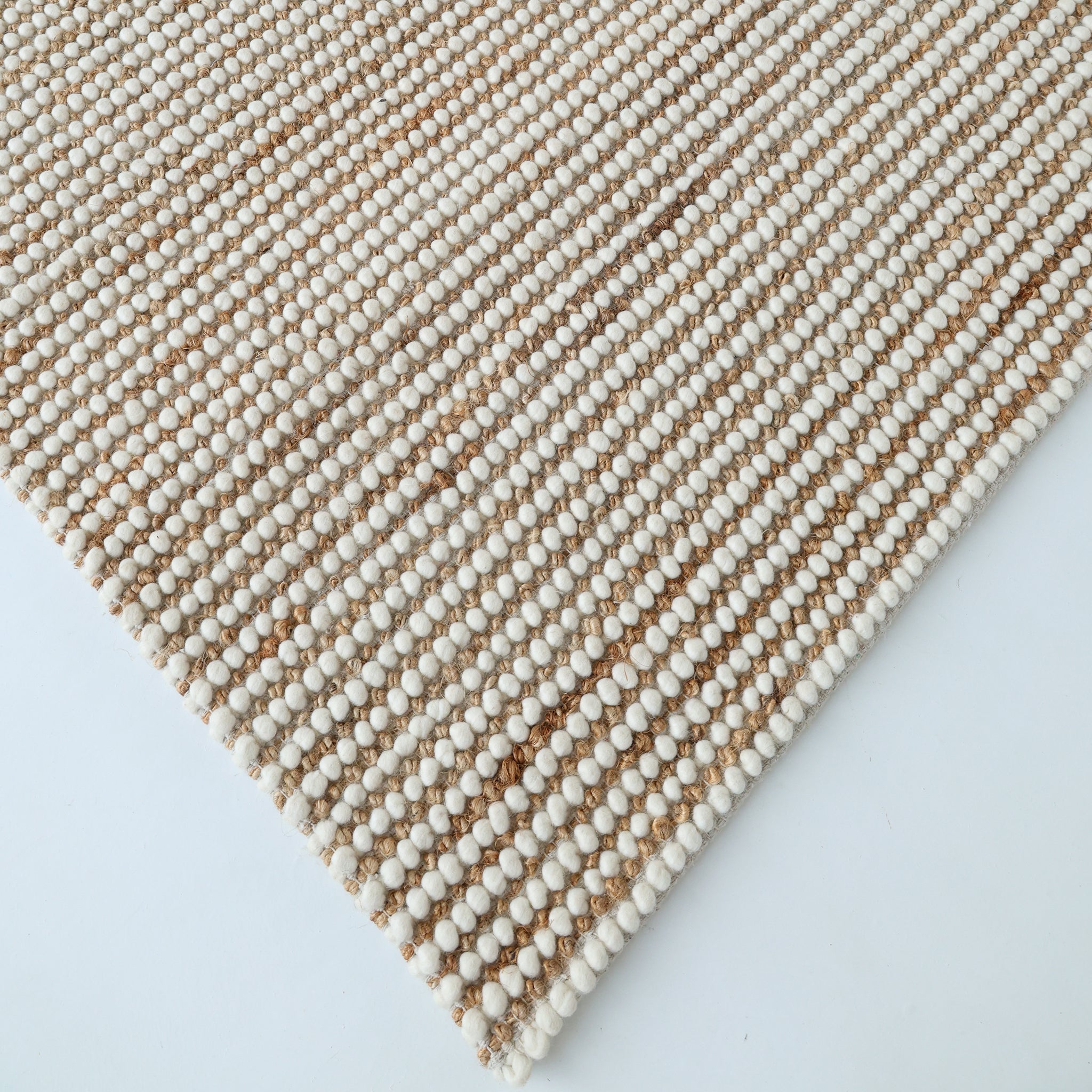Close-up of the RAMSHA HOME Solid Textured Loop Pile Woven Rug For Home Decor SRN-027, featuring alternating white beaded and natural tan fiber stripes. The area rug is displayed at an angle against a light background.