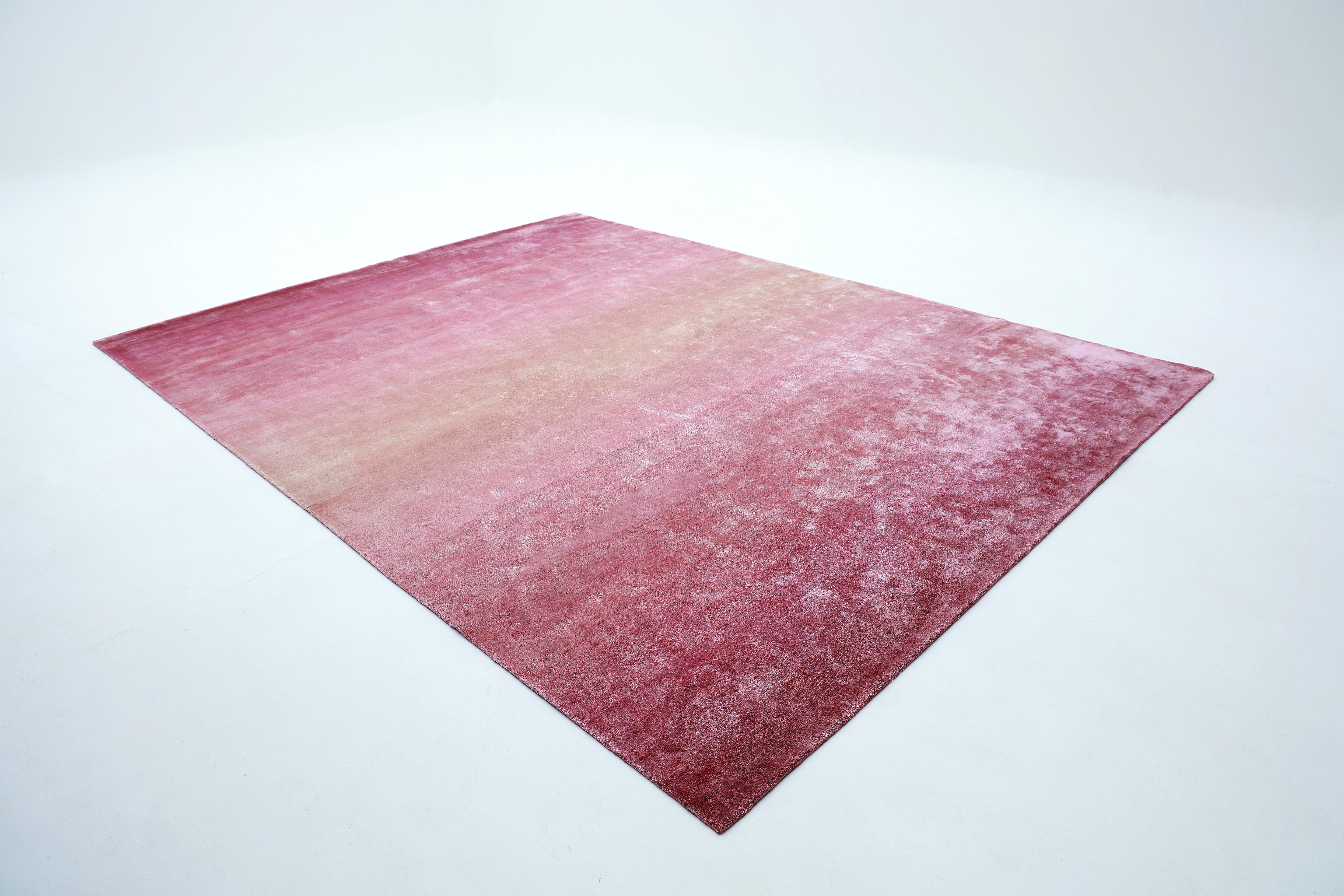 The RAMSHA HOME Rose Ombre Handmade Area Rug HTV 27 (300x400 cm) brings modern sophistication to a minimal, empty room with its soft Tencel gradient, fading from deep pink to light pink, on a plain white floor.