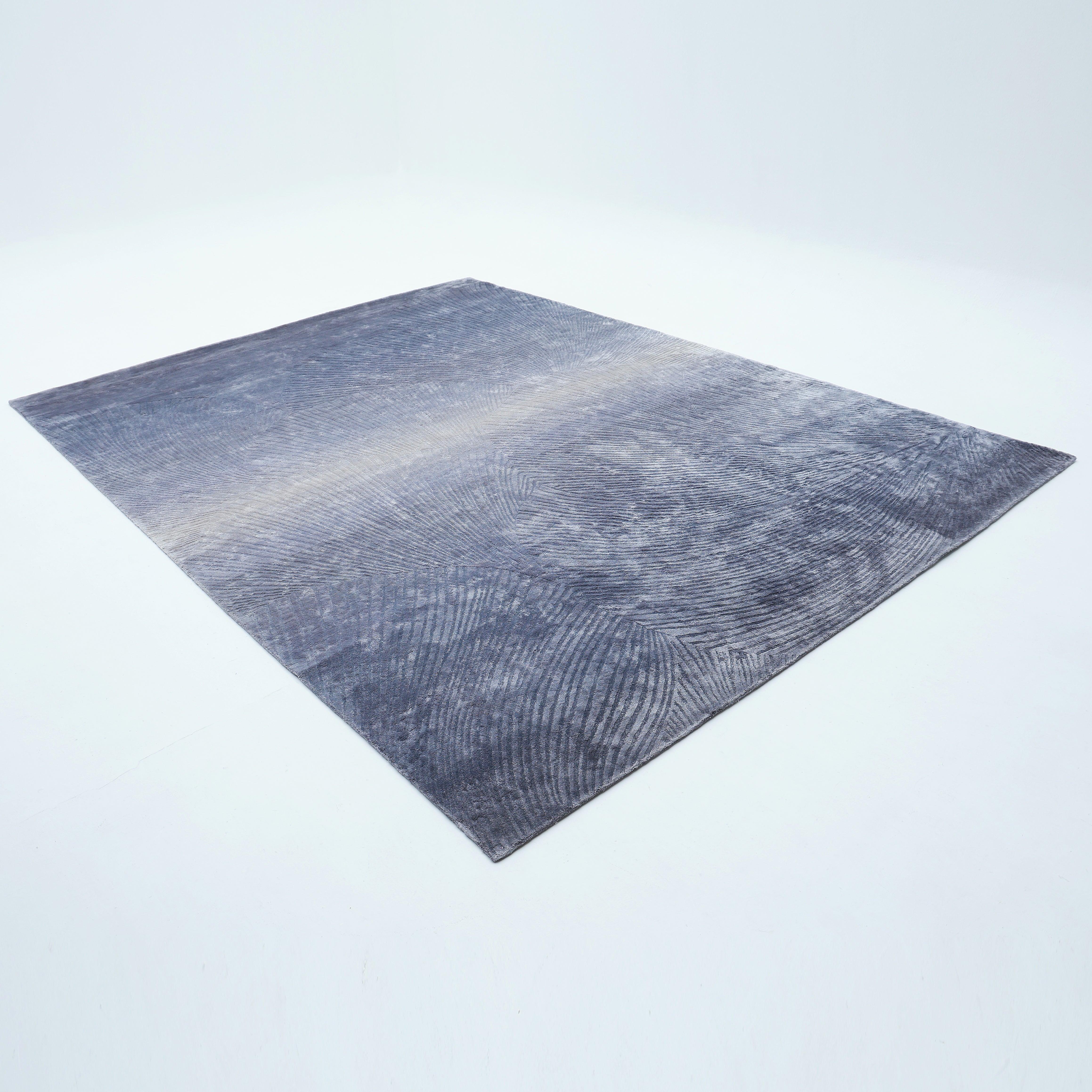 The RAMSHA HOME Blue Ginkgo Fan Handmade Rug HTV 29 (300x400 cm), a large rectangular piece with subtle textured patterns, lies flat on a white floor in a minimalist, well-lit space.