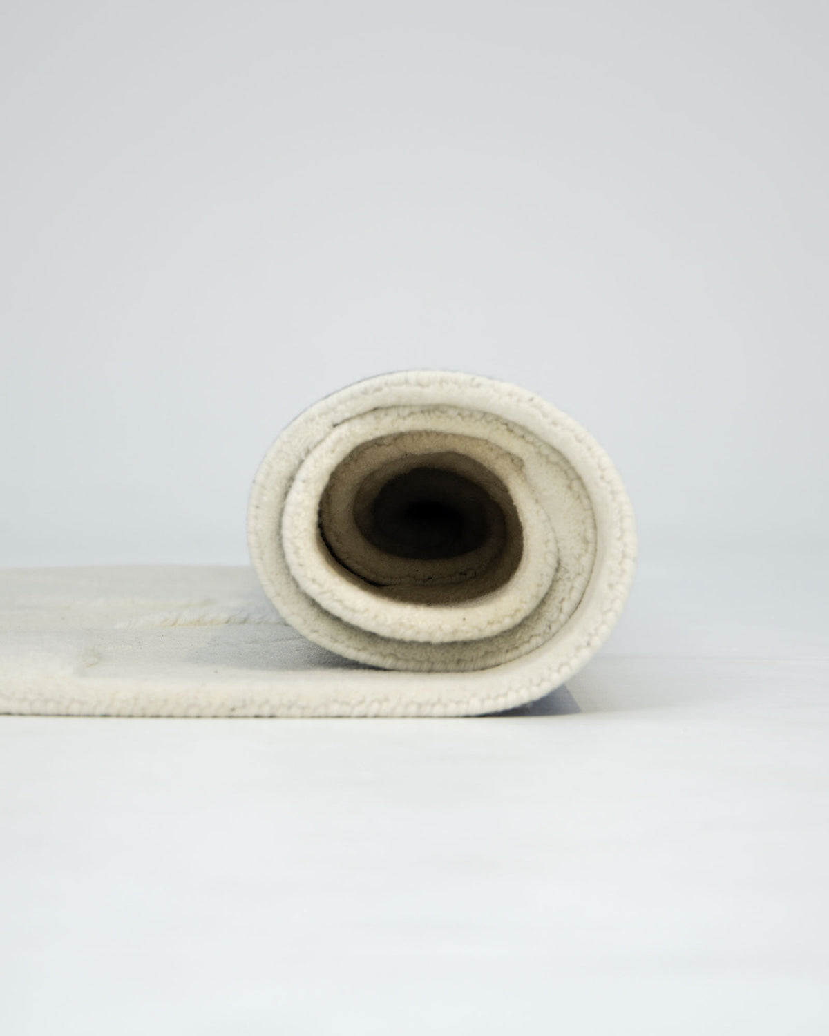 A rolled-up Creative Multi Color Wool & Cotton Handmade Rug - HTW 69 (200x300cm) by RAMSHA HOME is displayed on a plain white background, viewed from the side with the spiral of the roll visible.