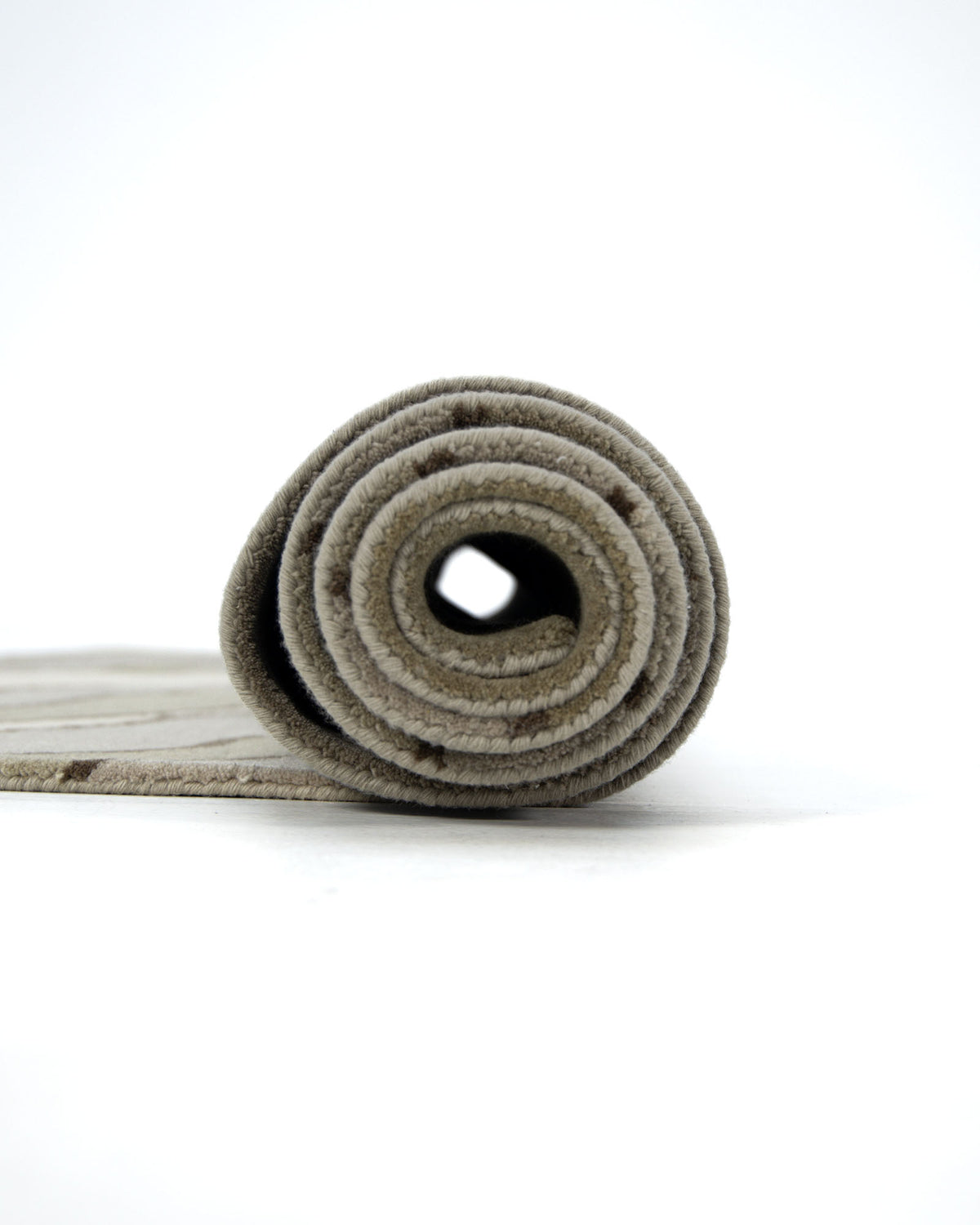 A close-up view of the RAMSHA HOME Beautiful Home Decor Handmade Carpet – HTW-66, a beige hand tufted wool rug, rolled up against a white background, highlighting the spiral pattern at one end.