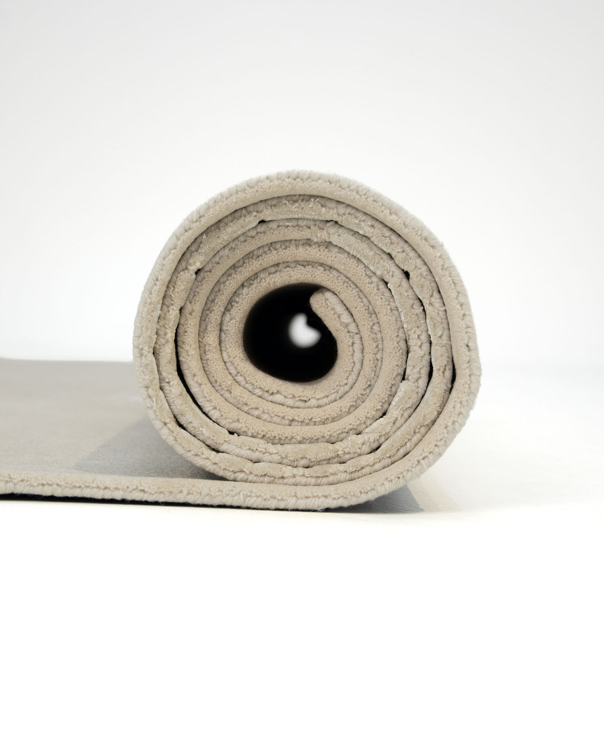 A light gray rolled-up Hand-Tufted Carpet For Home Decor HTWV-76 by RAMSHA HOME is displayed on a white background, viewed from the front. Its circular layers and soft texture evoke the appeal of a neutral floor covering that seamlessly complements any modern space.
