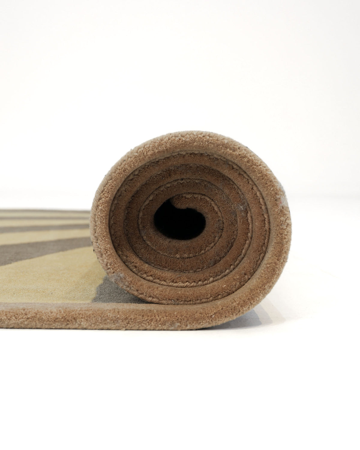 A close-up side view of the rolled-up Modern Mustard & Grey Wool Carpet HTW-30 by RAMSHA HOME, crafted from luxurious New Zealand wool, displayed on a white background.