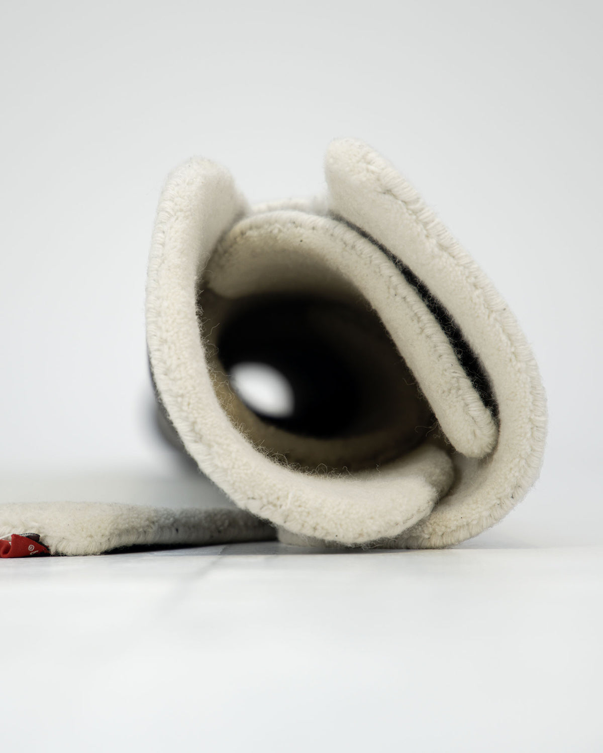 A close-up view of a rolled-up cream-colored fleece blanket with a soft texture, placed on a white surface beside the RAMSHA HOME Luxurious Brown & Beige Color Round Hand Tufted Rug - HTW 58 (200cm).