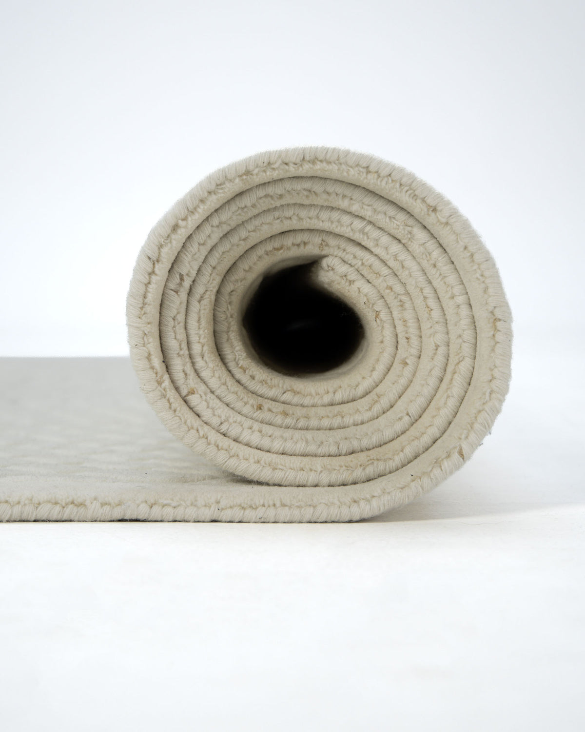 A close-up view of the RAMSHA HOME Handmade Decorative Area Rug - LKH-019 (200x300 cm) showcases its textured ivory-beige surface, rolled up and displayed against a white background.