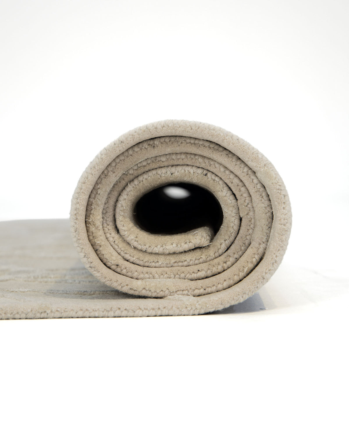 A close-up of the RAMSHA HOME Natural White Color Handmade Area Rug - HTWV-145 (200x300 cm) tightly rolled, highlighting its spiral layers from the side against a plain white background.