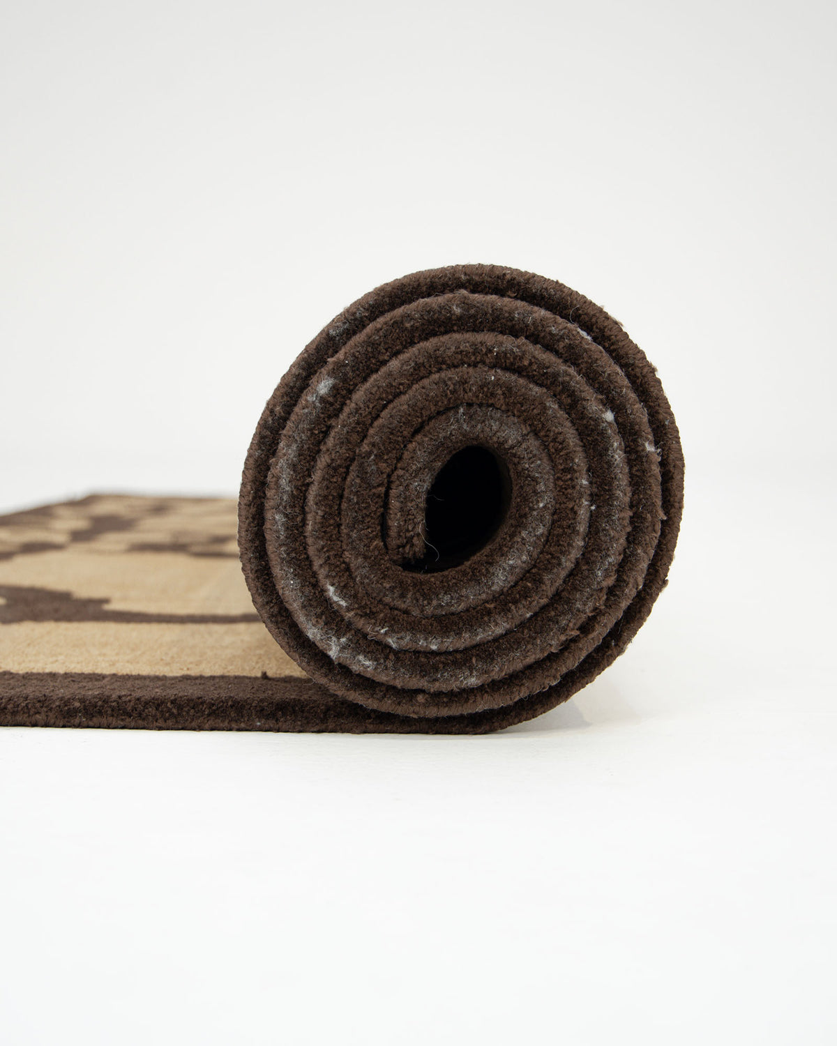 A rolled-up Multi Handmade Area Rug - HTP 21 (200x300cm) by RAMSHA HOME, featuring a modern brown and beige abstract design, is shown standing on its side against a plain white background.