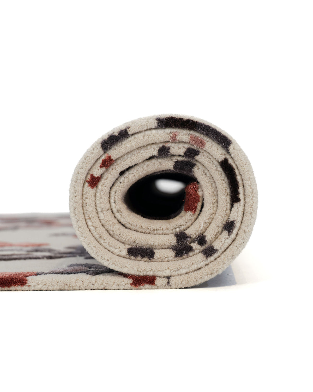 A side view of the RAMSHA HOME Multi Color Handmade Area Rug HTWV-119, rolled up to display its beige surface adorned with small, scattered red and black shapes, set against a white background.