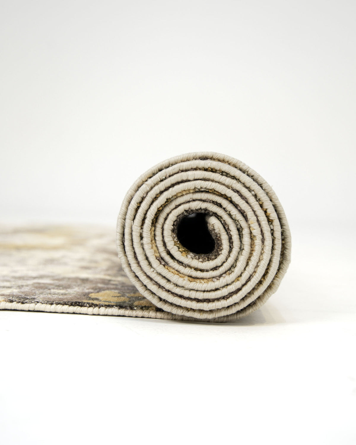 A rolled-up RAMSHA HOME Bamboo Silk & Cotton Carpet HKWB-014 with a neutral, patterned design sits on a white surface against a plain white background.