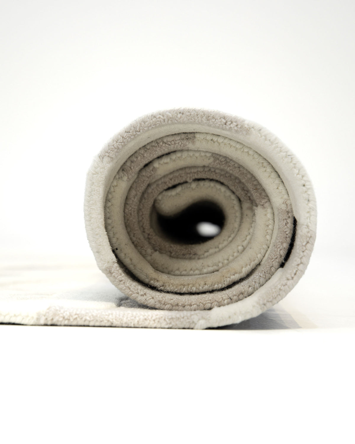 A close-up view of the Handcrafted Living Room Area Rug – HTWV-127 by RAMSHA HOME, rolled up to display its soft texture and layered construction, captured against a plain white background.