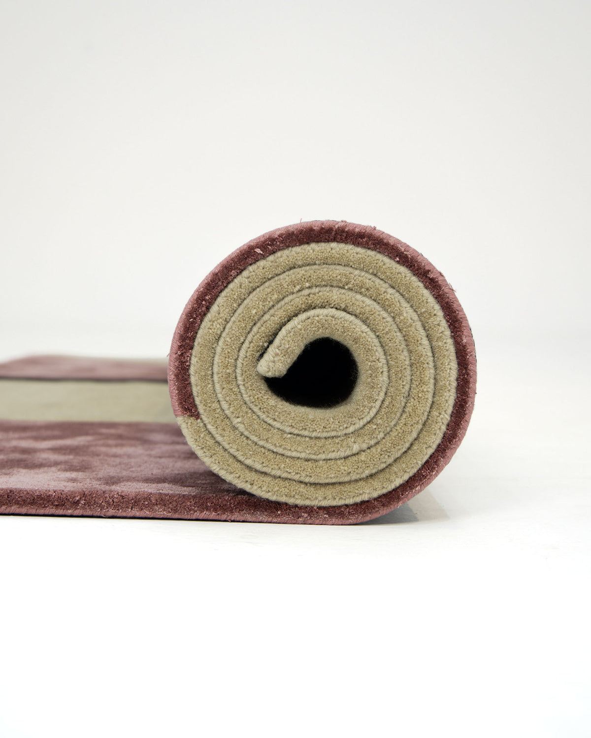 The RAMSHA HOME Multi Color Handmade Rug HTWV-20 is shown rolled up, featuring a maroon outer layer and a beige inner layer, set on a white surface against a plain white background.