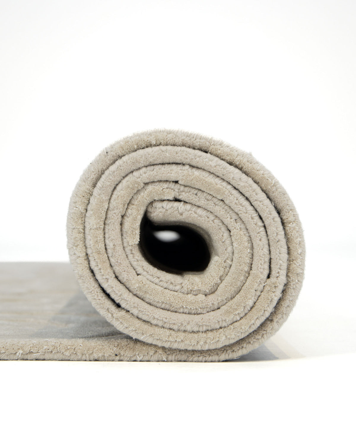 A close-up of the Rectangle Modern Handmade Rug 200x300 CM HTWV-197 by RAMSHA HOME, rolled up and displayed from the side against a plain white background. The spiral form reveals its plush texture, showcasing the rug’s soft surface and understated abstract design.