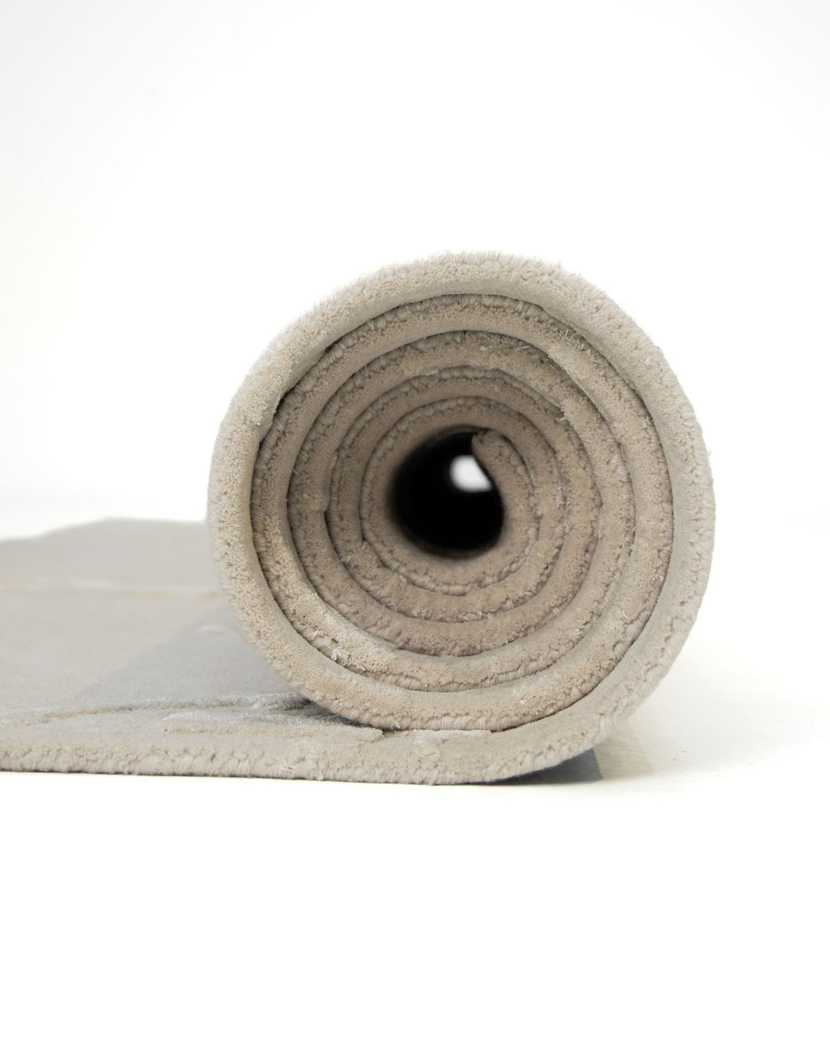 A close-up view of the RAMSHA HOME Handmade Beige Color Decor Rug- HTWV 115, rolled up on a white background and highlighting the circular layers at one end.