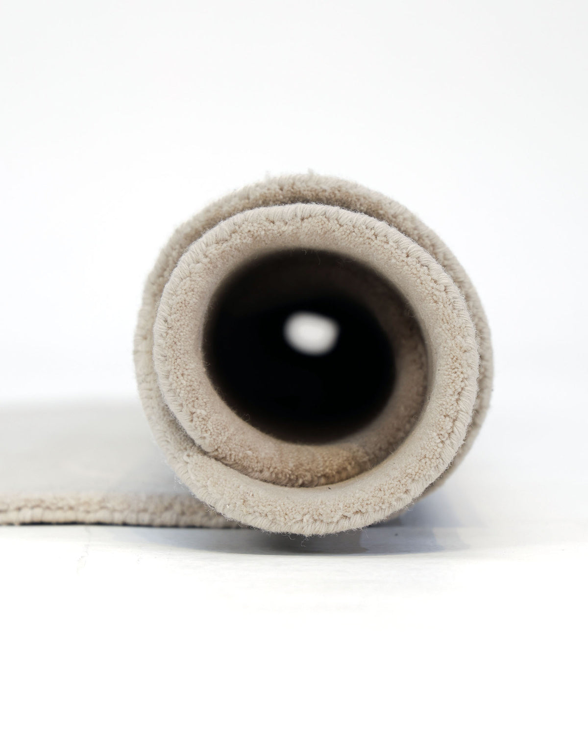 A close-up view of the Handmade Rose Shape Rug HTW 106 by RAMSHA HOME, rolled up on a white background, highlighting its soft texture and distinctive circular rose shape.