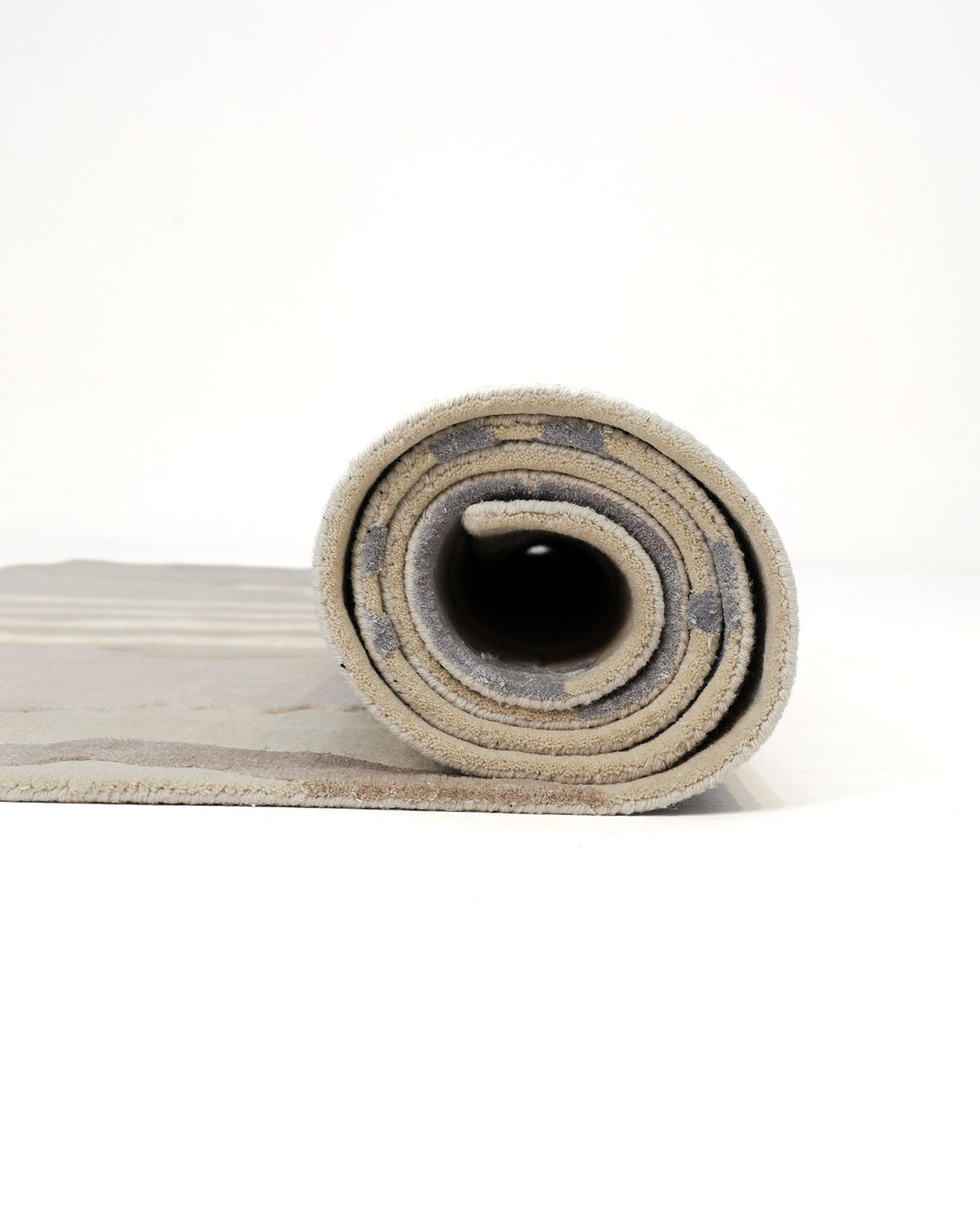 A rolled-up Classic Rectangle Handmade Area Rug—HTWV 177 (300x400 cm) by RAMSHA HOME, featuring subtle beige tones with gray stripes and positioned upright against a white background, evokes the refined simplicity of a neutral abstract rug.