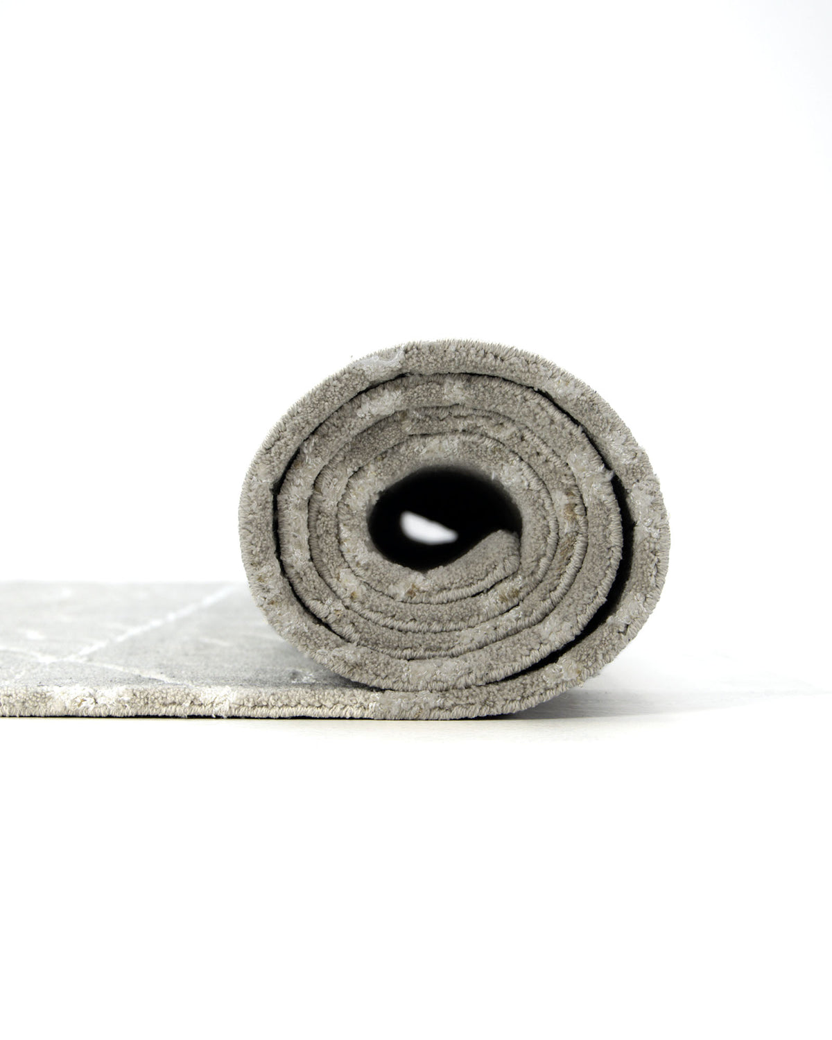 A close-up of a rolled-up RAMSHA HOME Modern Rectangle Area Rug Multi Color HTP-18 on a white background, with the rug partially unrolled to reveal its inner circular layers.