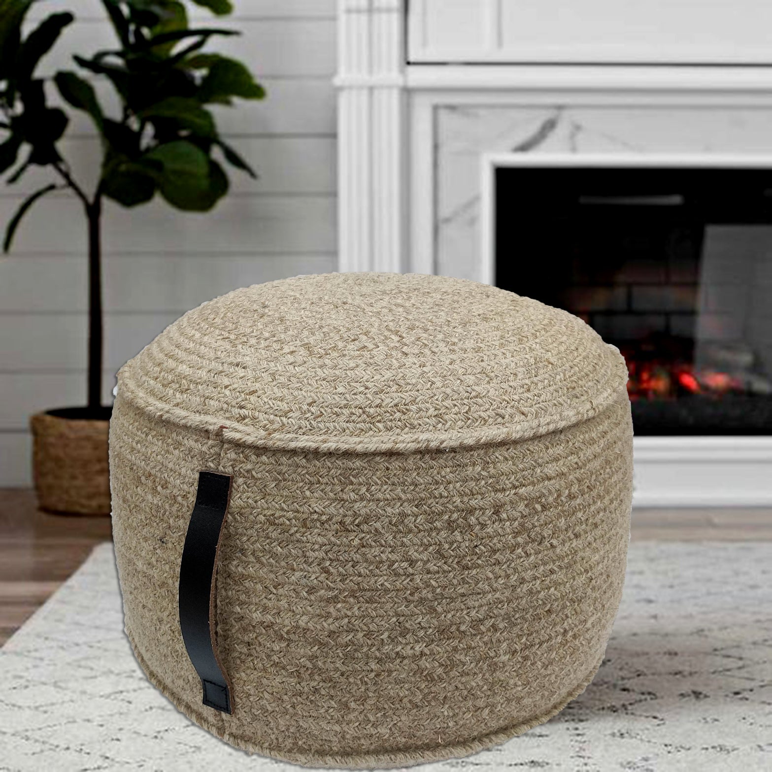 The RAMSHA HOME Natural Wool Pouf With Leather Handle PF-052 sits on a light rug by the fireplace with a potted plant, bringing charm to this cozy living space.