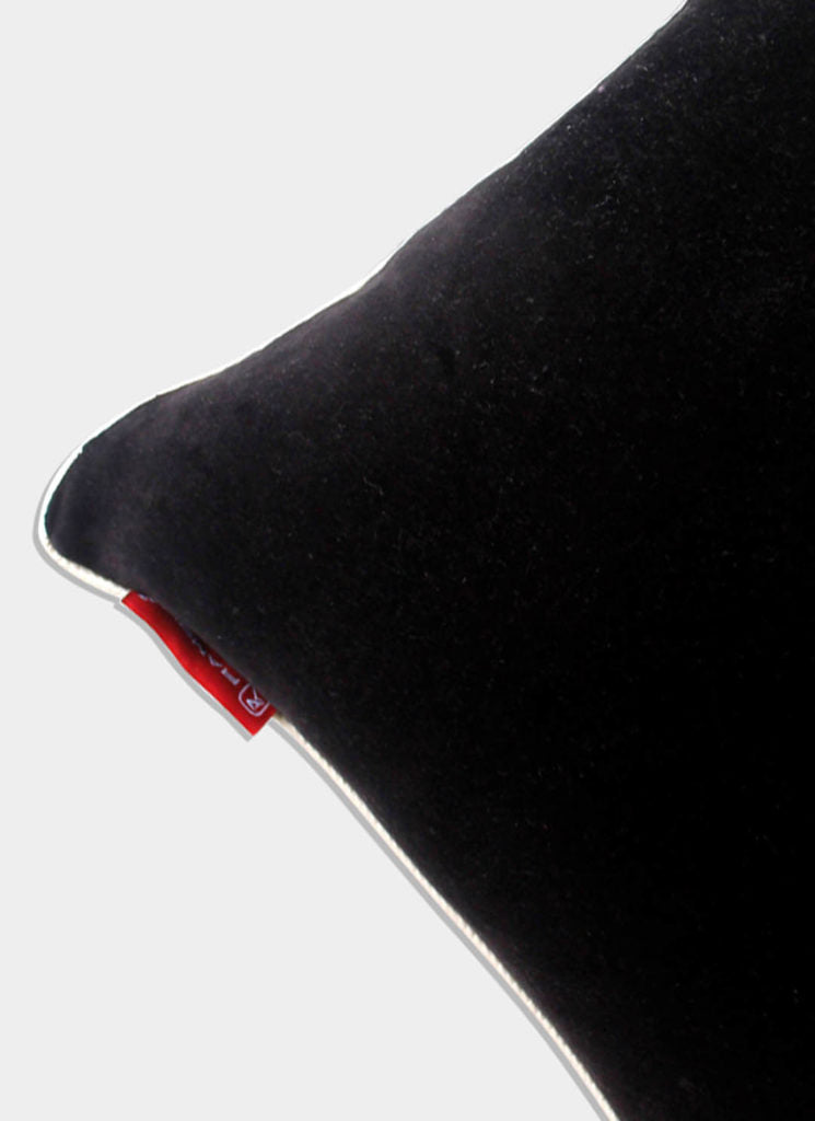 A close-up of RAMSHA HOME’s Polyester Cushion Plain With Filler cs-233 shows its black polyester fabric, white piping, and a small red tag. The plush filling adds elegance, displayed against a plain light background.