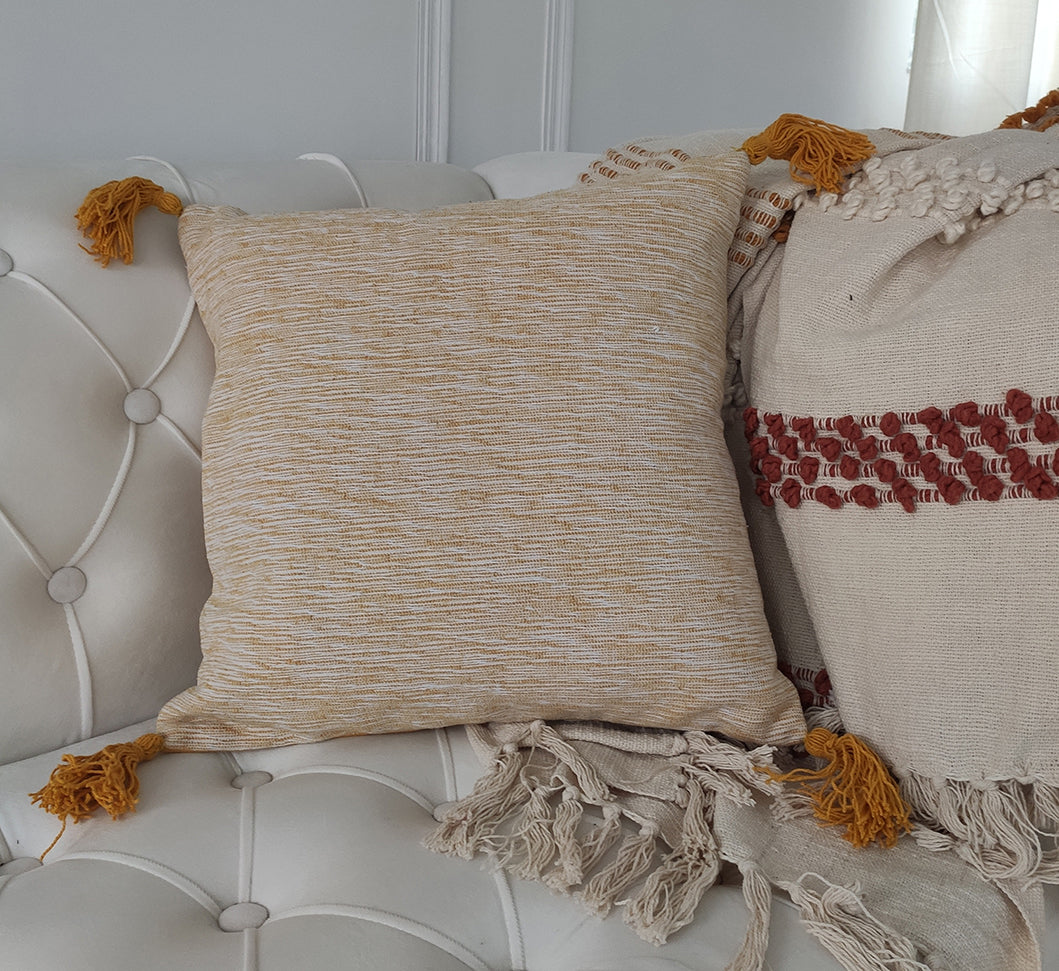 A Black & White Color Polyester Cushion with Filler by Ramsha Home (CS 216) rests on a sofa beside a cream throw with red accents and fringed edges, adding elegance to modern interiors.
