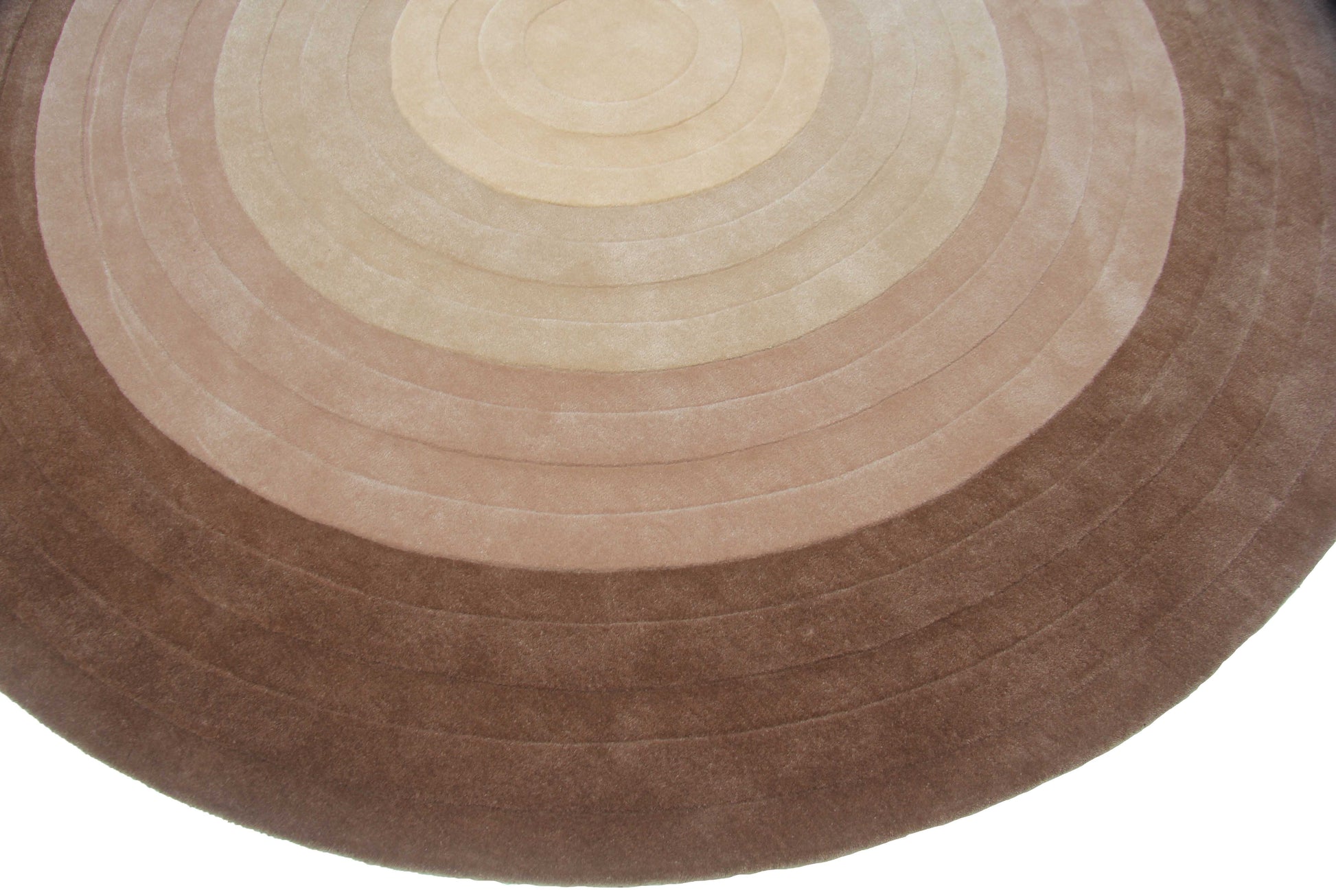 The RAMSHA HOME Home Decor Concentric Circle Handmade Carpet – HTW-51 features concentric rings in beige and brown, creating a gradient effect from the center. Its hand-tufted wool texture appears soft and plush.