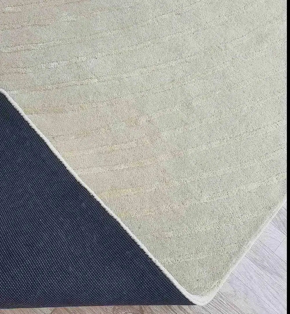 The RAMSHA HOME Luxurious Multi Color Wool & Cotton Handmade Rug - HTWV 64 (300x400cm) is partially lifted at one corner, revealing its dark textured underside and light wooden floor—an elegant handtufted piece for versatile style.