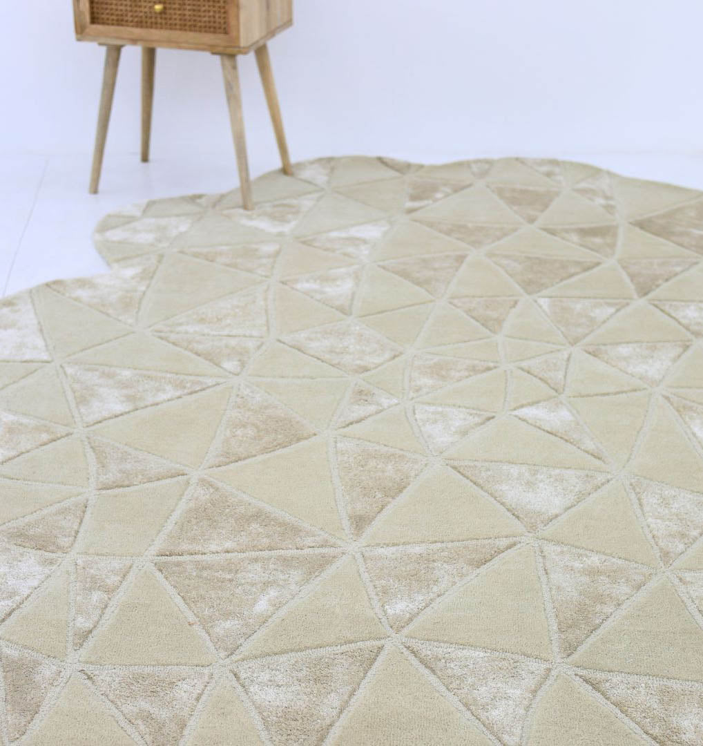 The RAMSHA HOME Handmade Decor Multi Color Rug HTWV-94 features an irregular scalloped edge and cream/beige triangle pattern. A small wooden table with angled legs is partially visible in the background.