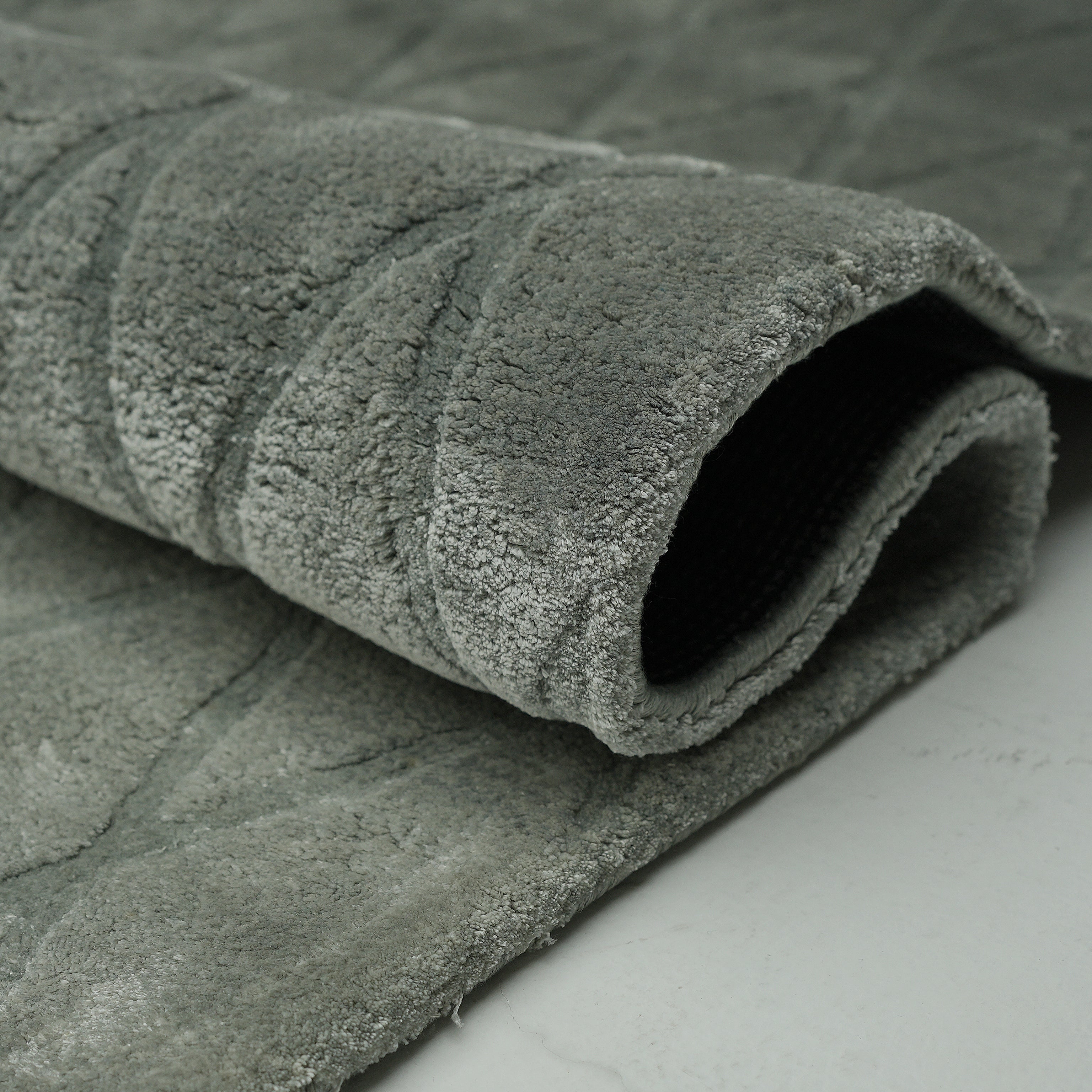 A close-up of the RAMSHA HOME Steel Diamond Handmade Rug HTV 28 (300x400 cm) highlights its soft, plush surface, gray diamond pattern, and dark woven underside—an elegant modern touch for any space.