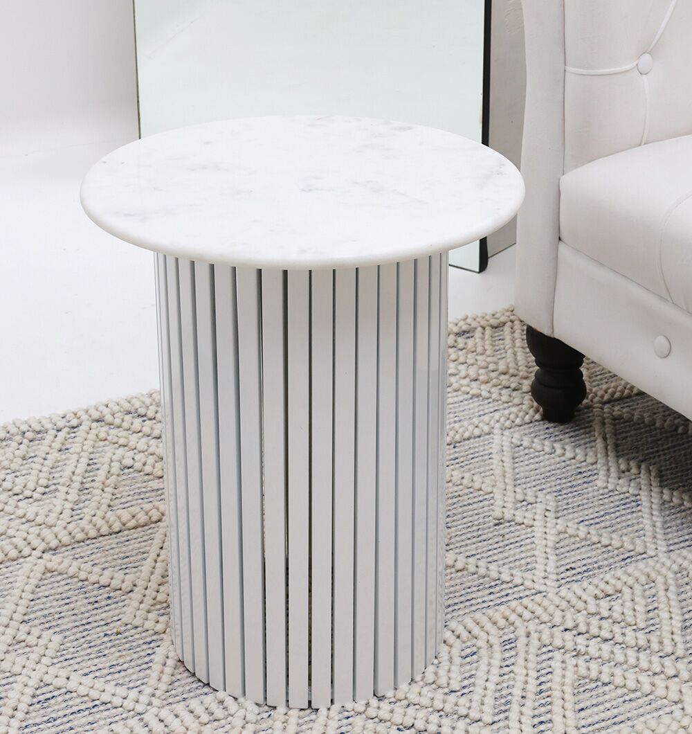The Modern White Marble Center Table AD23-12 by RAMSHA HOME, with a cylindrical base and vertical metallic slats, rests on a textured rug beside a white upholstered sofa.