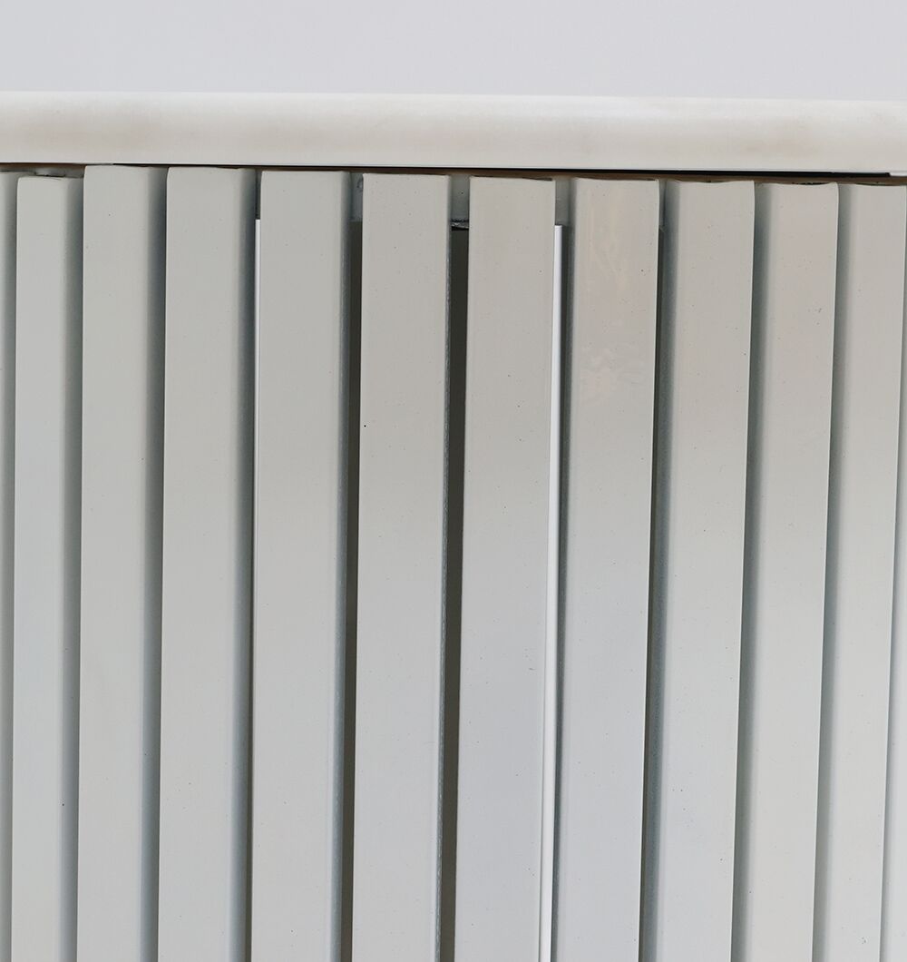 Close-up of a white metal radiator with vertical rectangular panels and rounded top edge, placed beside the Modern White Marble Center Table AD23-12 from RAMSHA HOME, set against a plain white background.