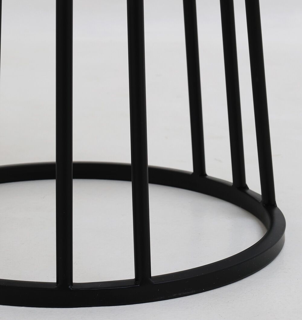 Close-up of the lower part of the Linea Round Marble Accent Table by RAMSHA HOME, showing its black metal base with vertical rods connected to a circular ring, resting on a white surface.