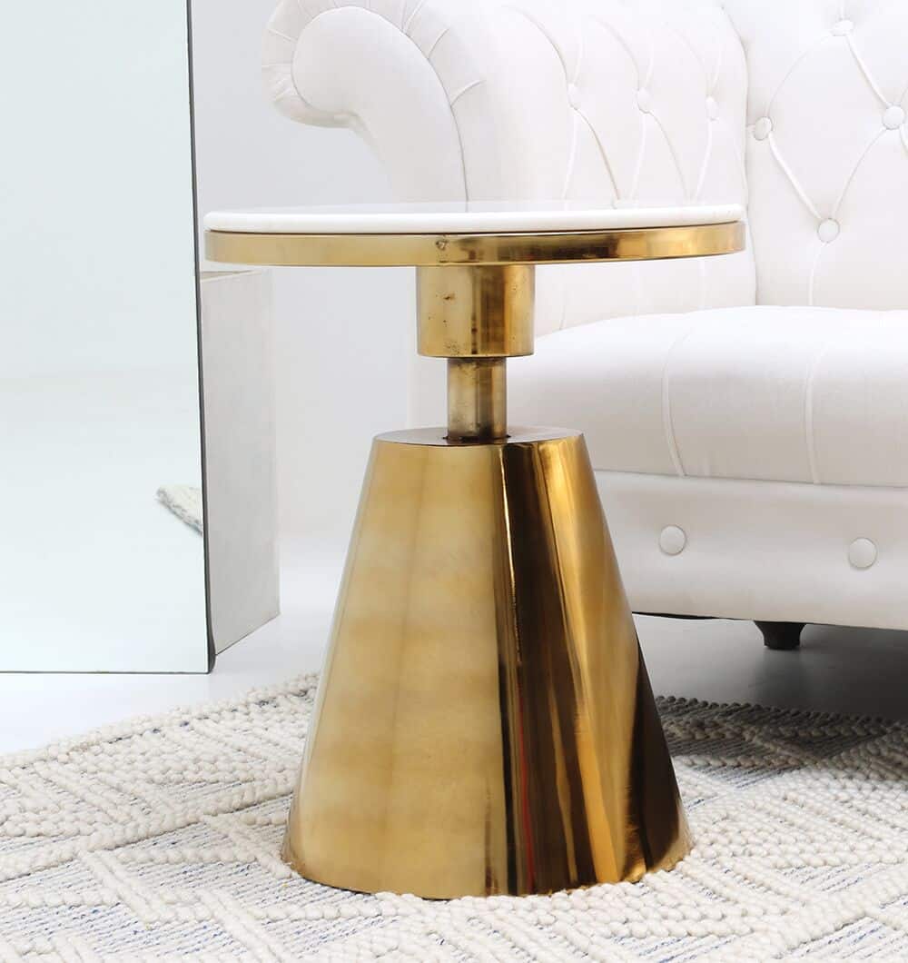 The Aurelia Luxe Marble & Iron Accent Table AD25-26 by RAMSHA HOME, featuring a glossy gold base and white marble top, sits on a textured rug beside a white tufted sofa, bringing modern charm to the space.