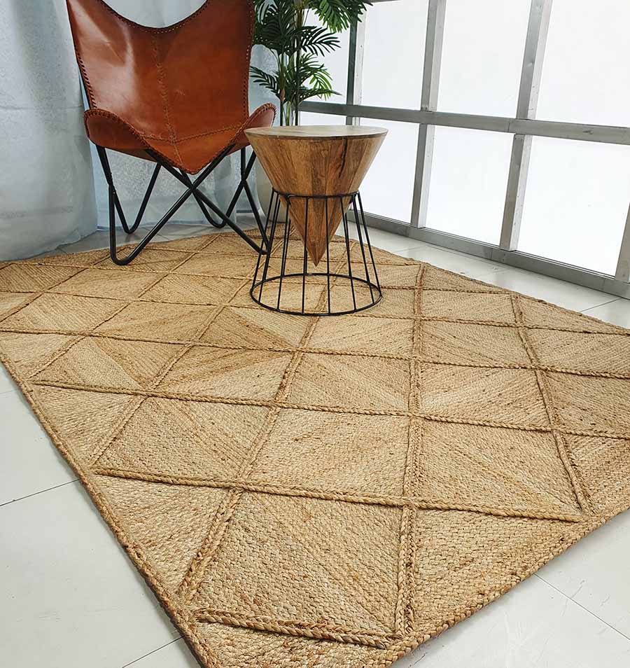 A modern living space with the RAMSHA HOME Amazing Handmade Jute Rug Living Room - BR 084, a brown leather butterfly chair, a small wood table with wire metal base, and a green plant near a large window.